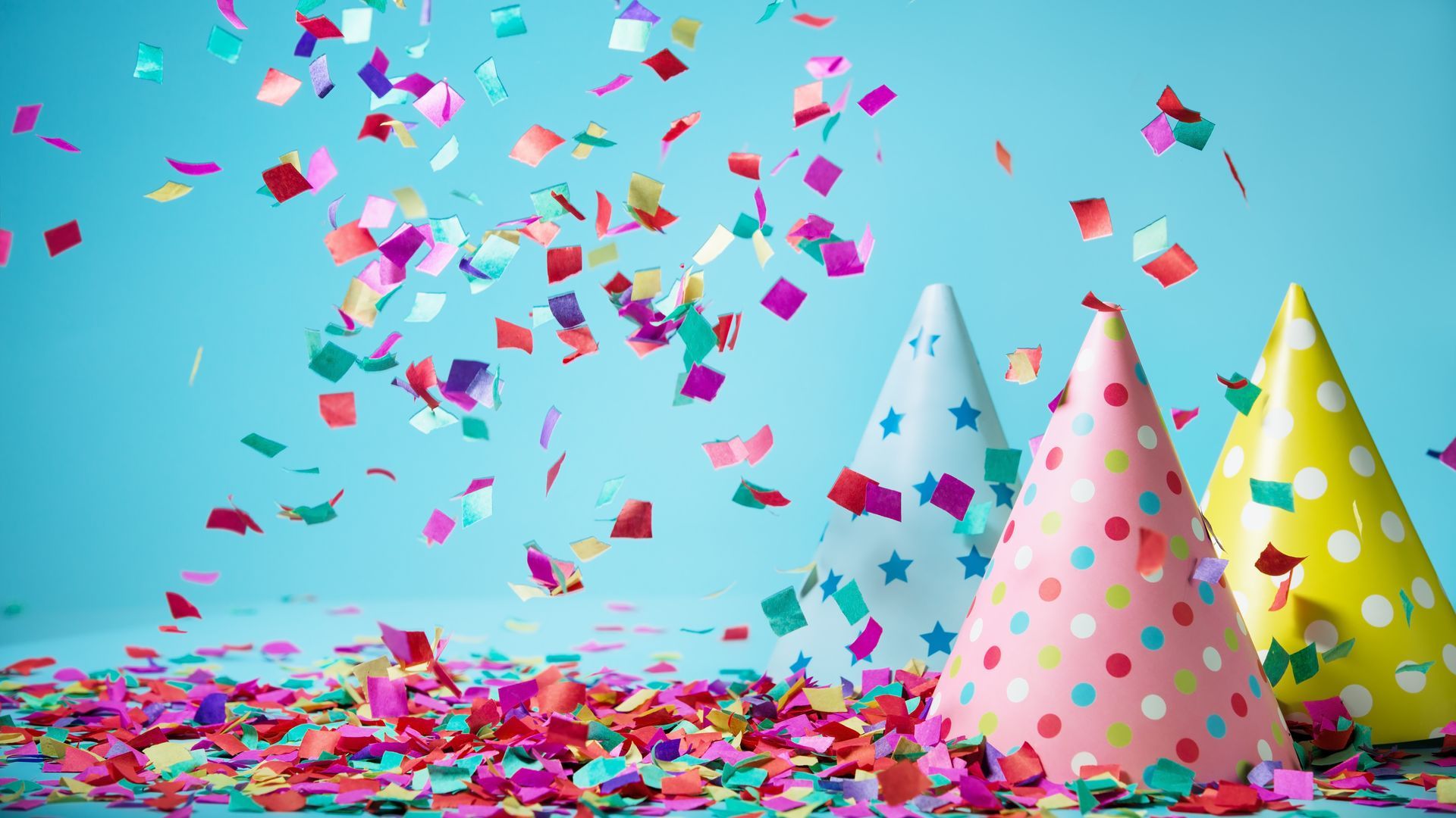 Party hats and confetti are falling on a blue background.