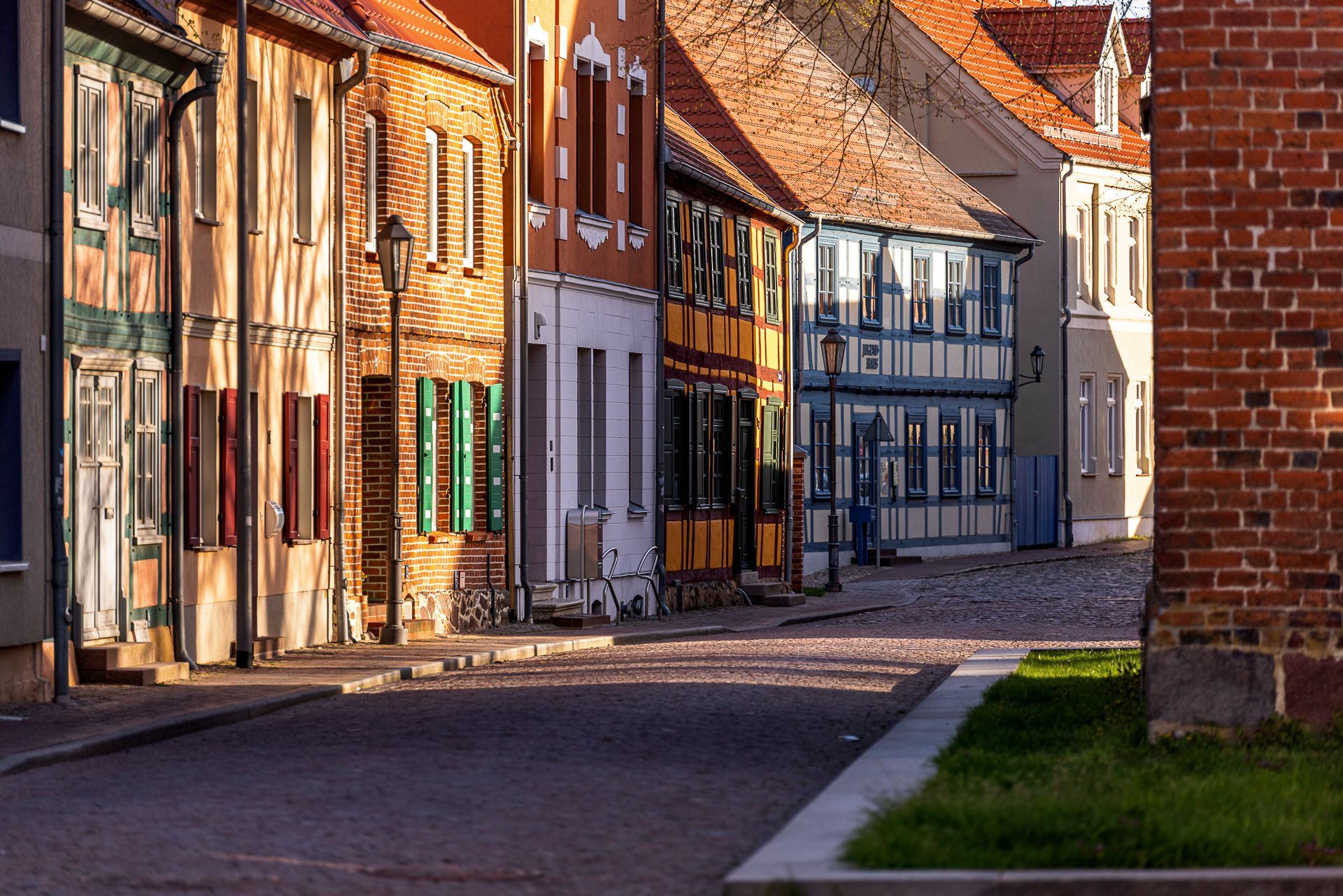 Eine Reihe farbenfroher historischer Gebäude in einer Kopfsteinpflasterstraße, beleuchtet von warmem Sonnenlicht.