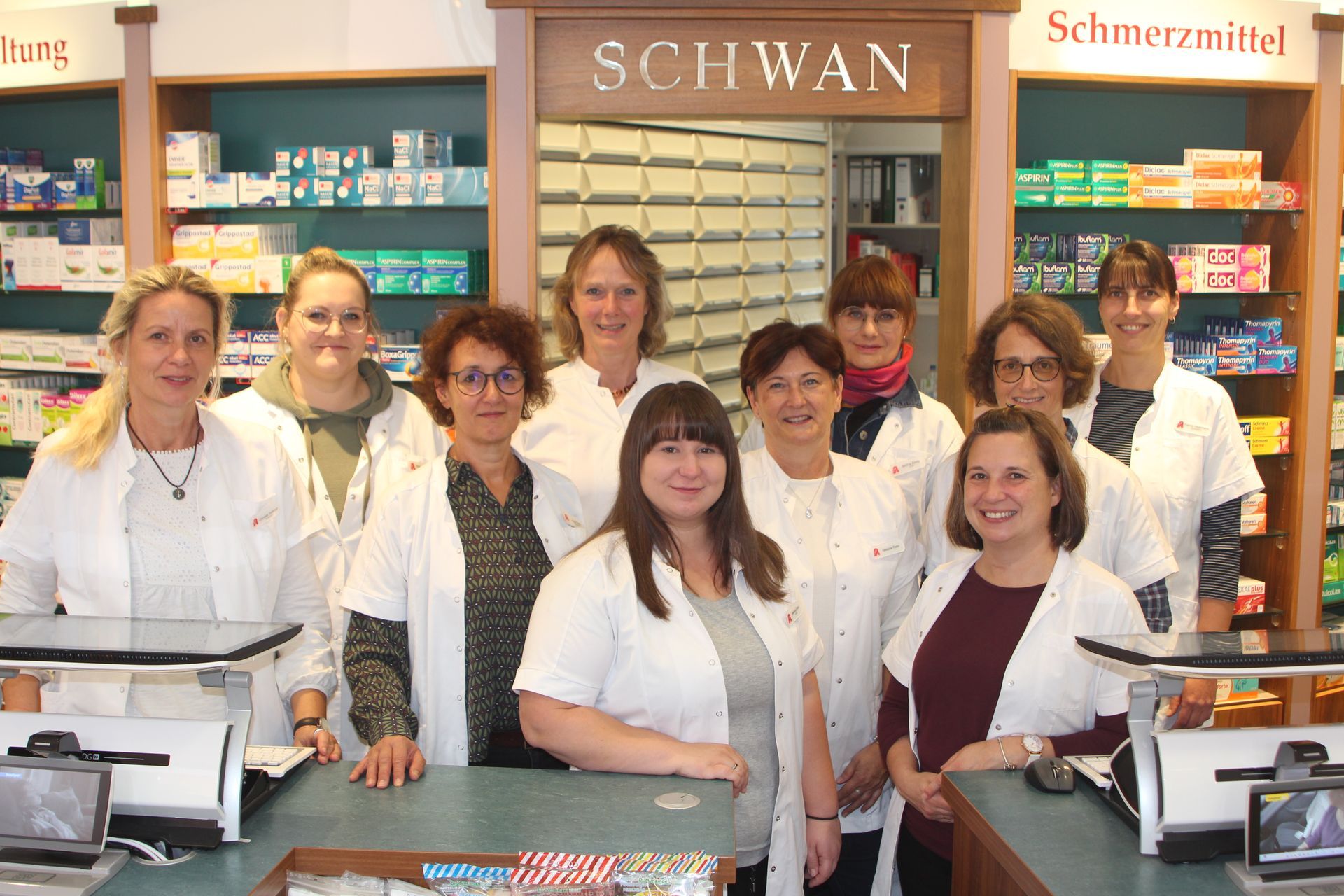 Apotheker in weißen Kitteln stehen hinter einem Tresen in der „Schwan“-Apotheke.