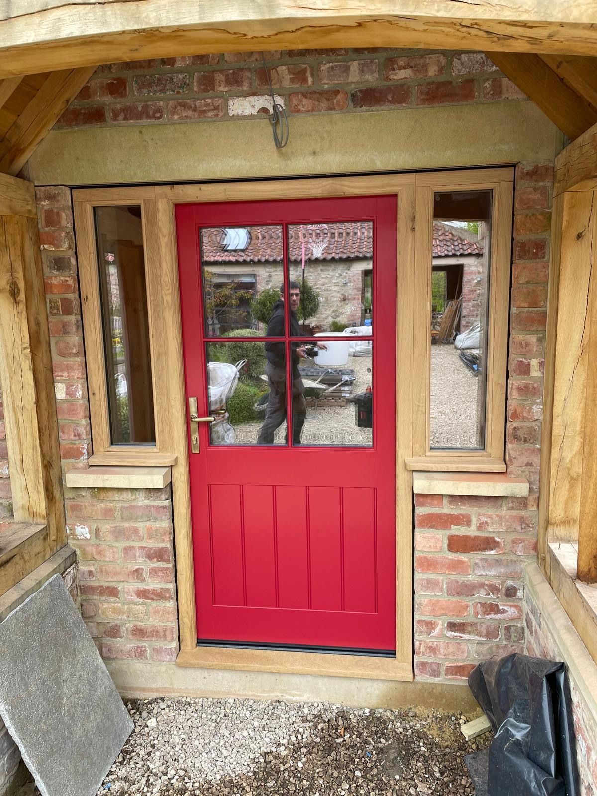 A red door is sitting in front of a brick building.