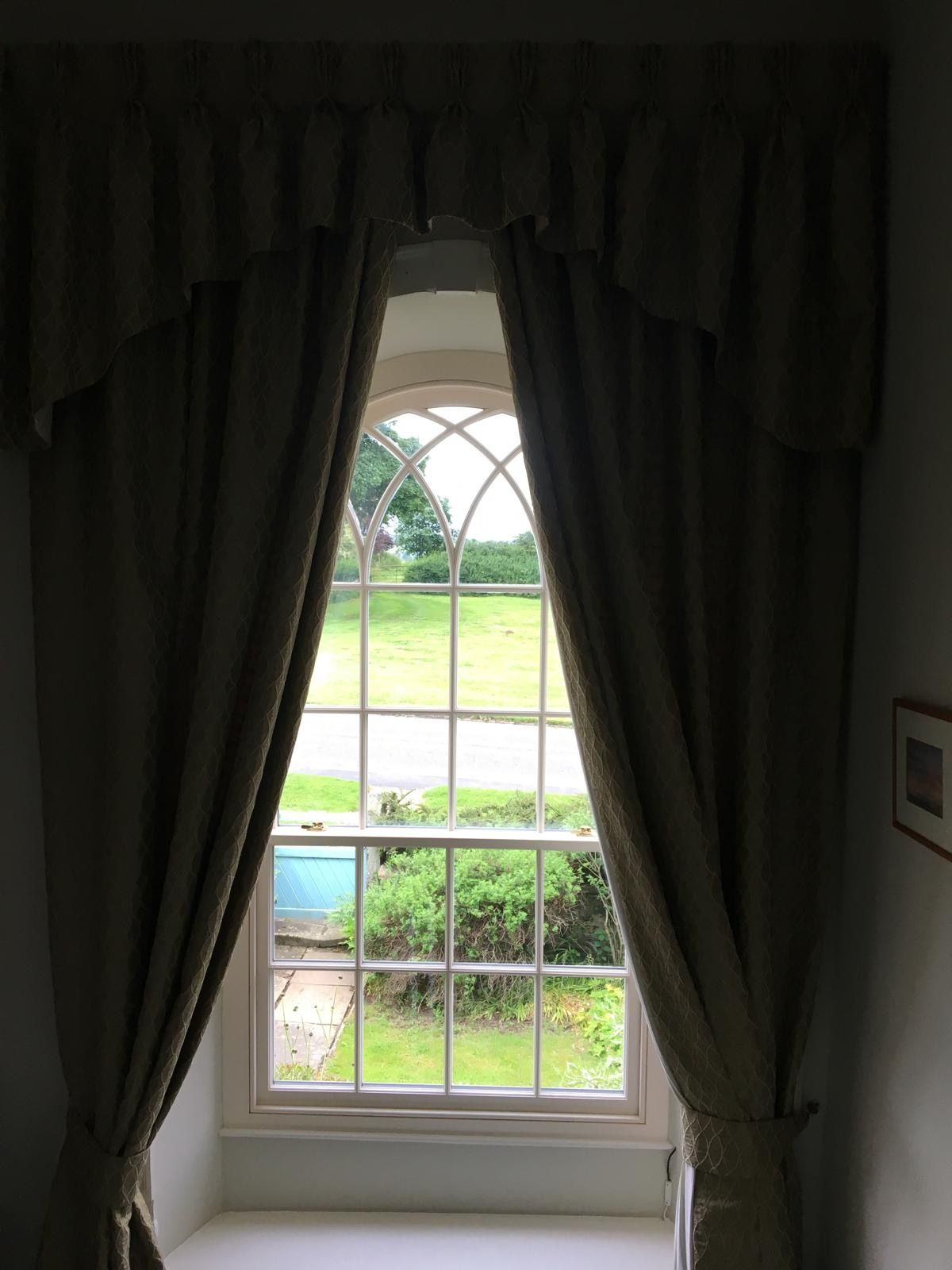 A window with curtains and a view of a field.