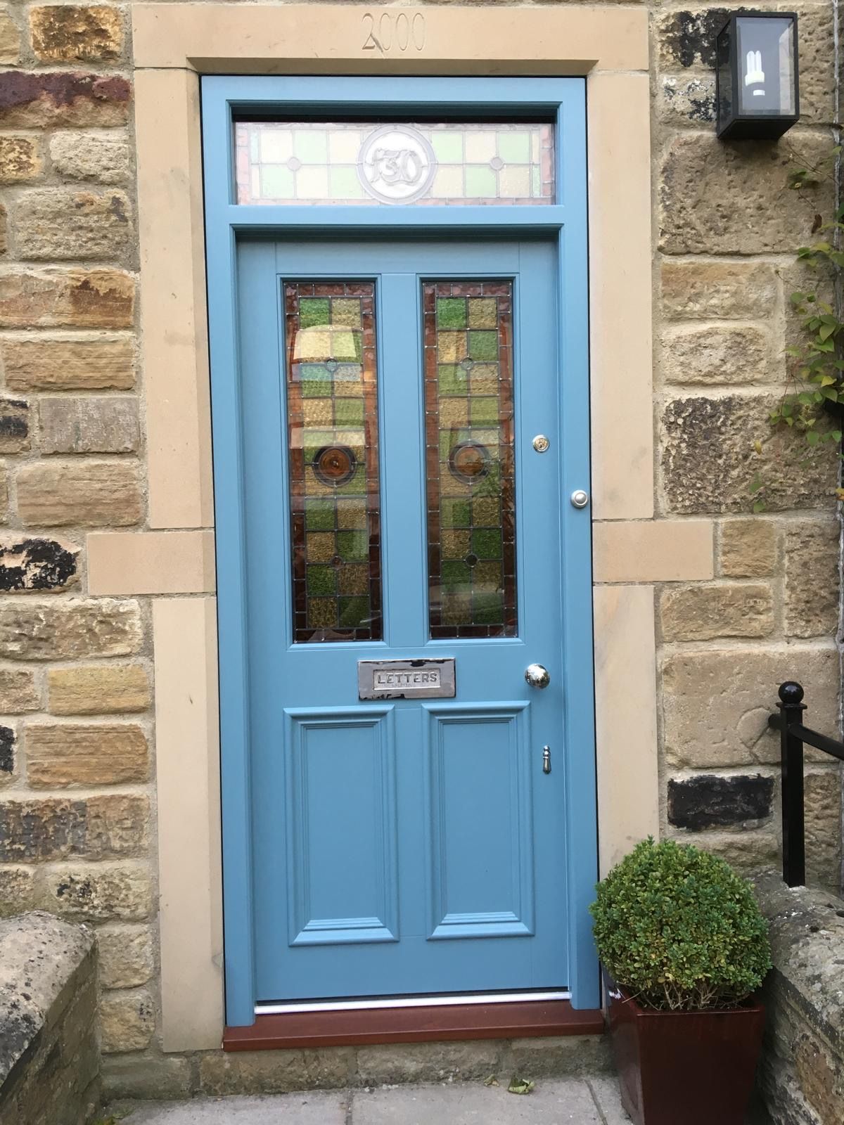 A blue door with a stained glass window is on a brick building