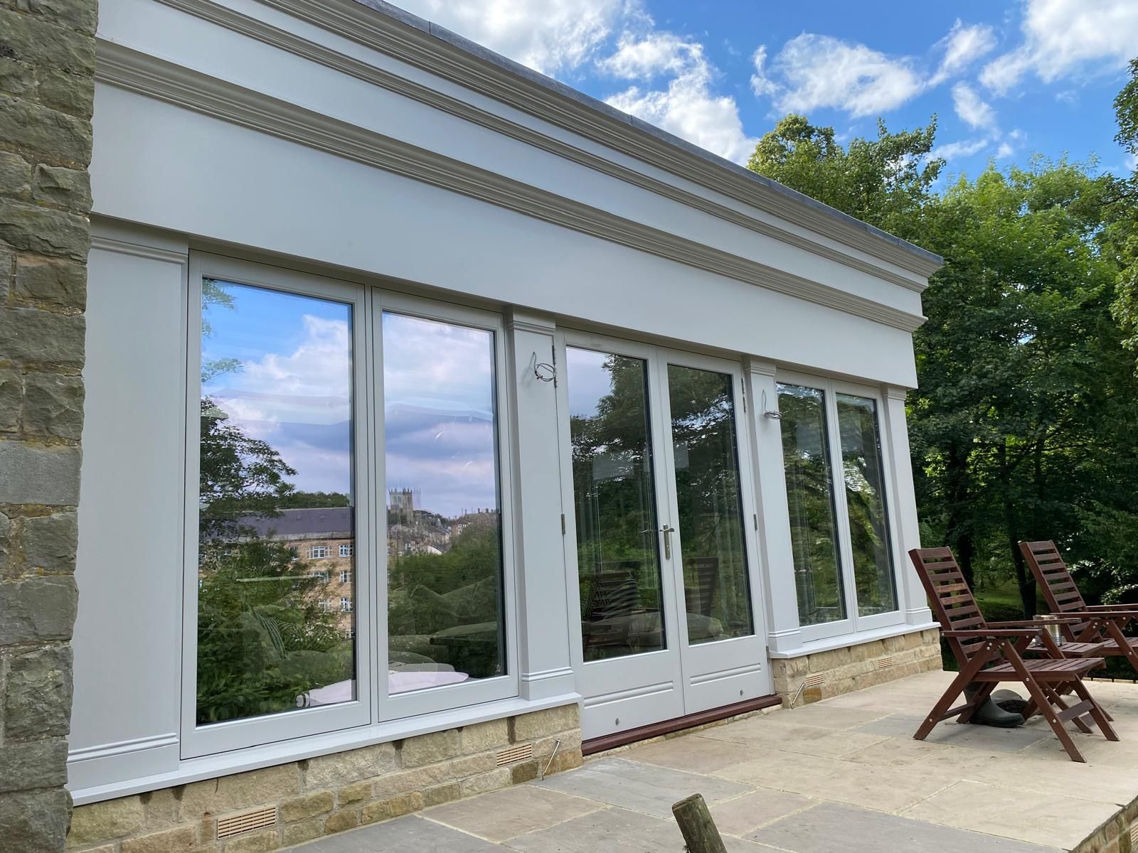 A large building with a lot of windows and chairs on the patio.
