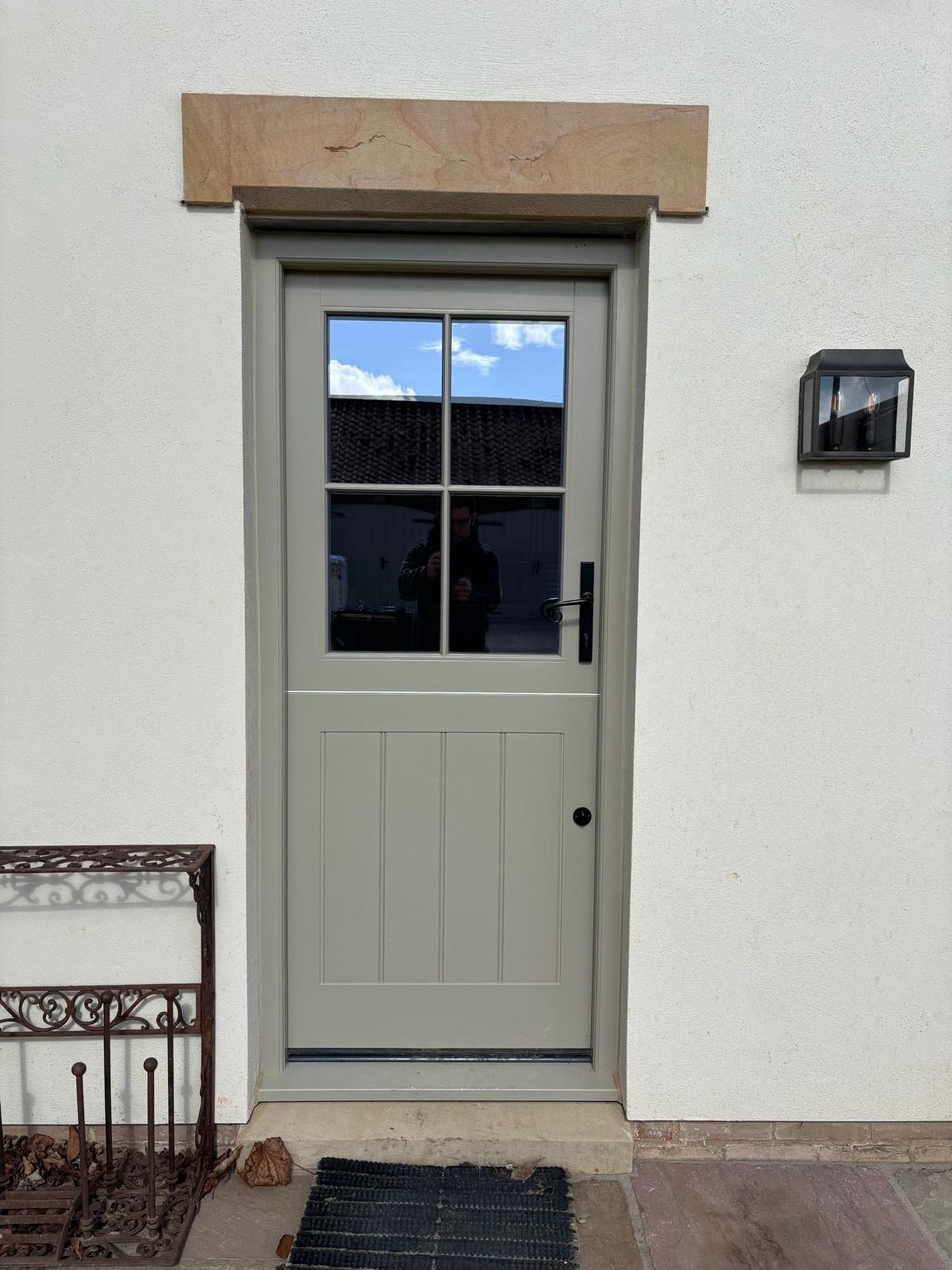 A white door with four windows on a white wall.