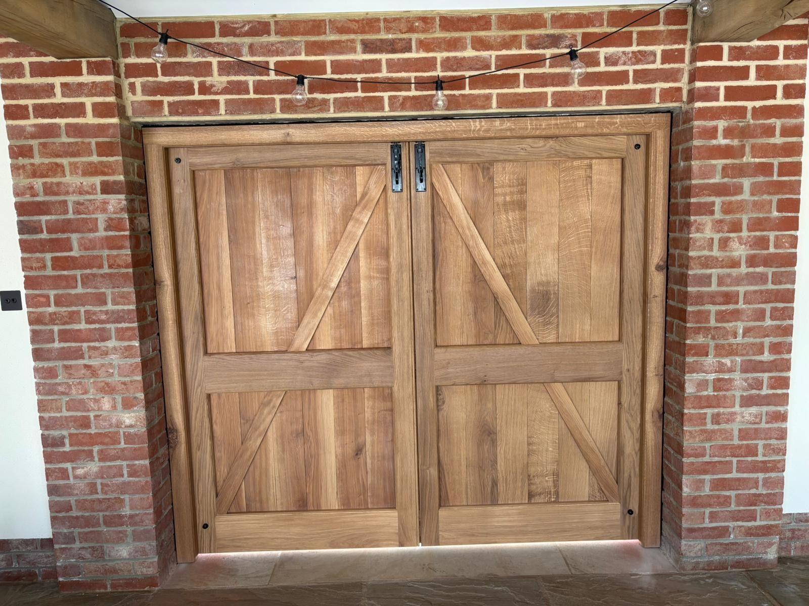 A pair of wooden garage doors on a brick wall.