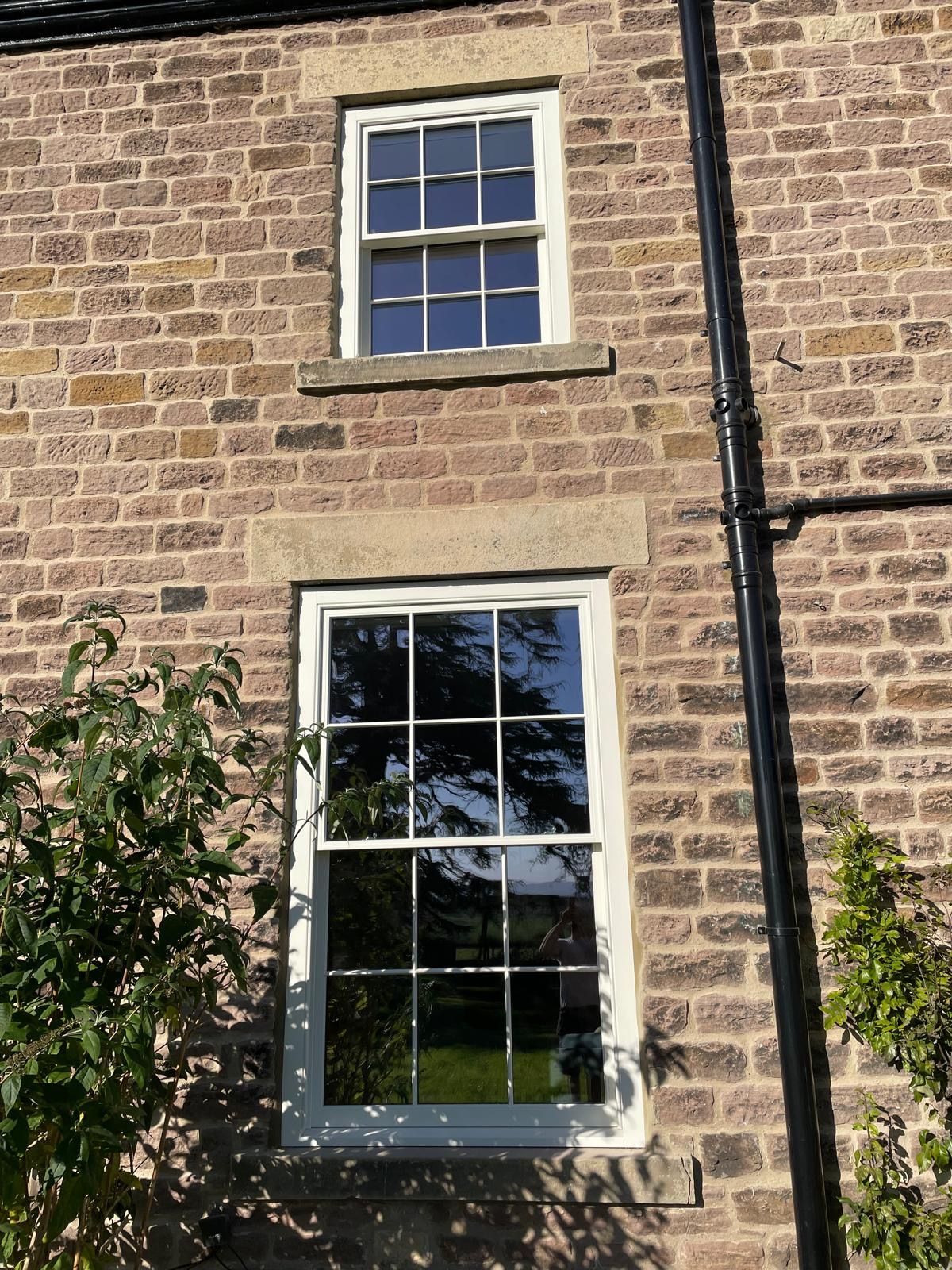 A brick building with a white window and a black pipe