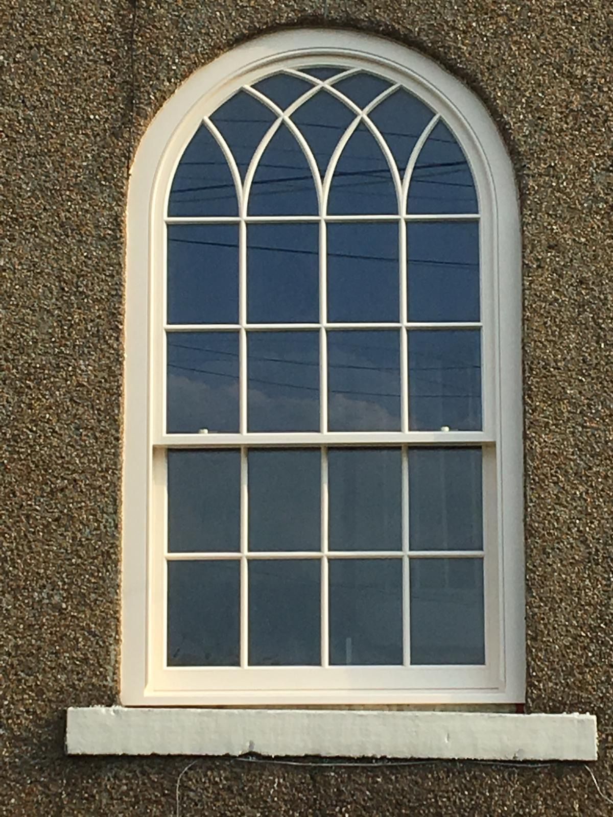 A window with a white frame is on a concrete wall