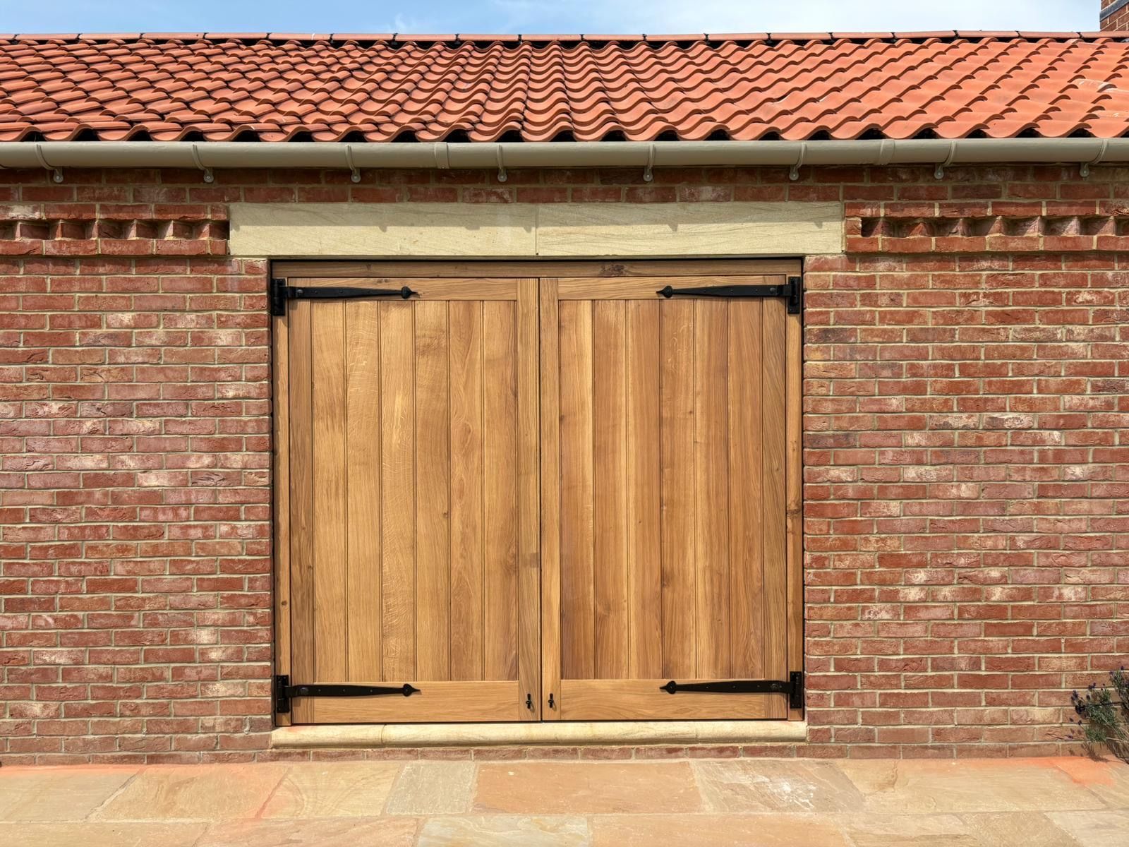 A brick building with a wooden garage door and a red tile roof.