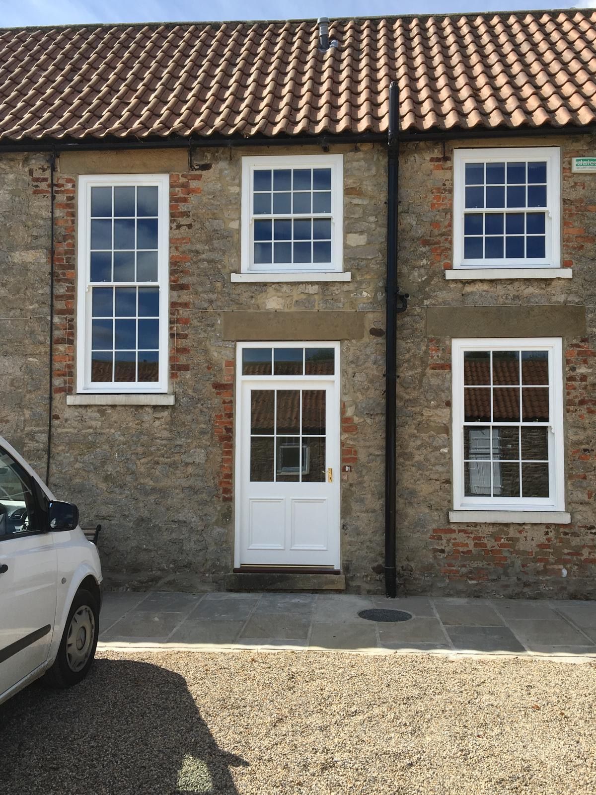 A white van is parked in front of a brick building