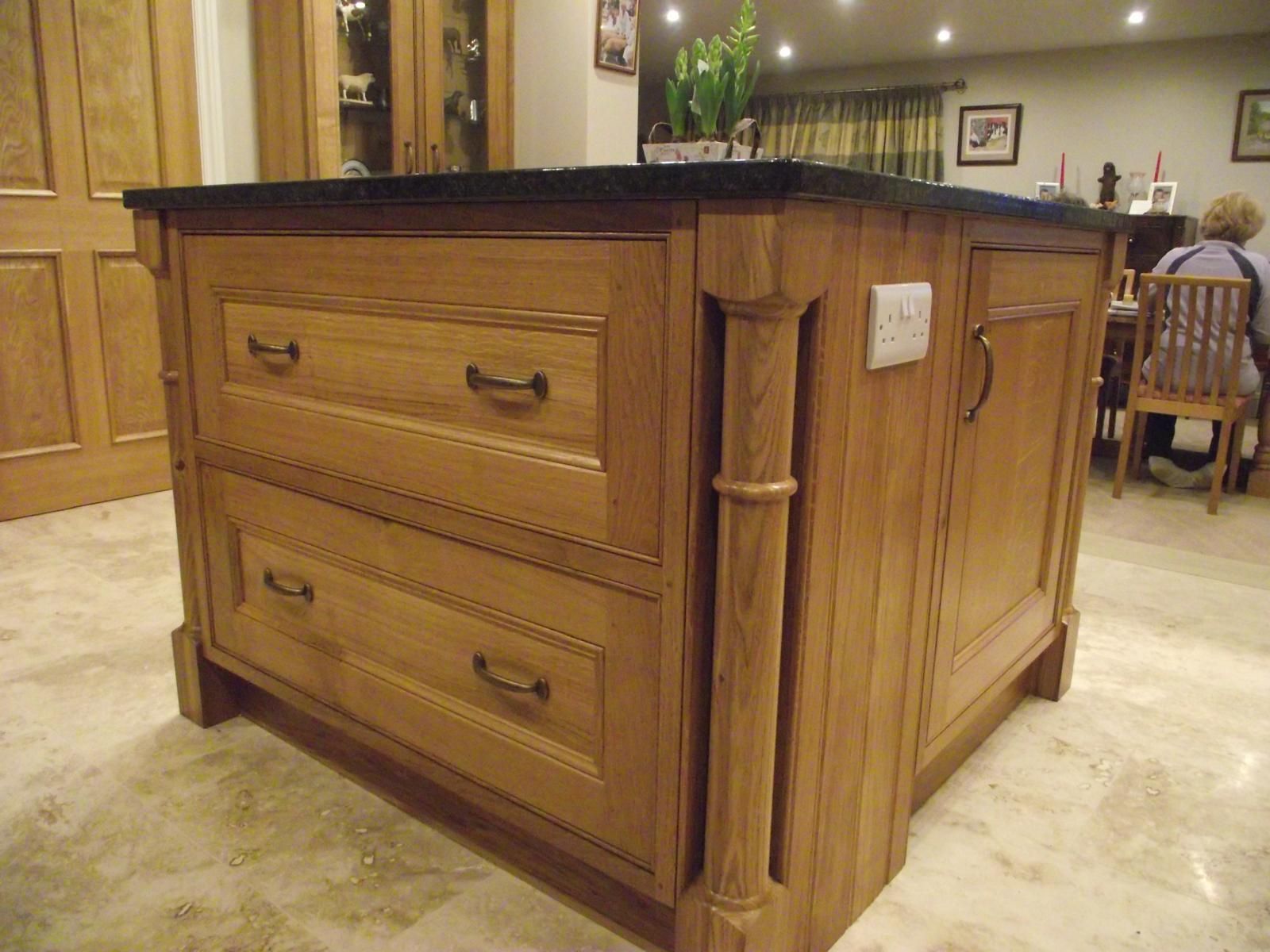A kitchen island with drawers and a granite counter top