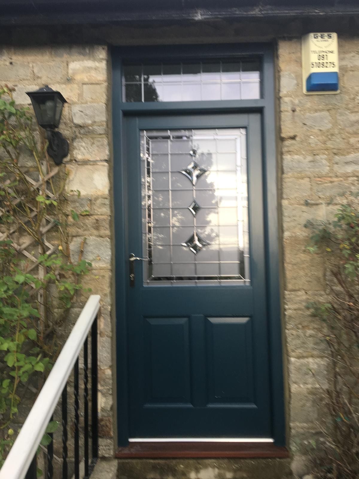 A blue door with a stained glass window is on a stone building.