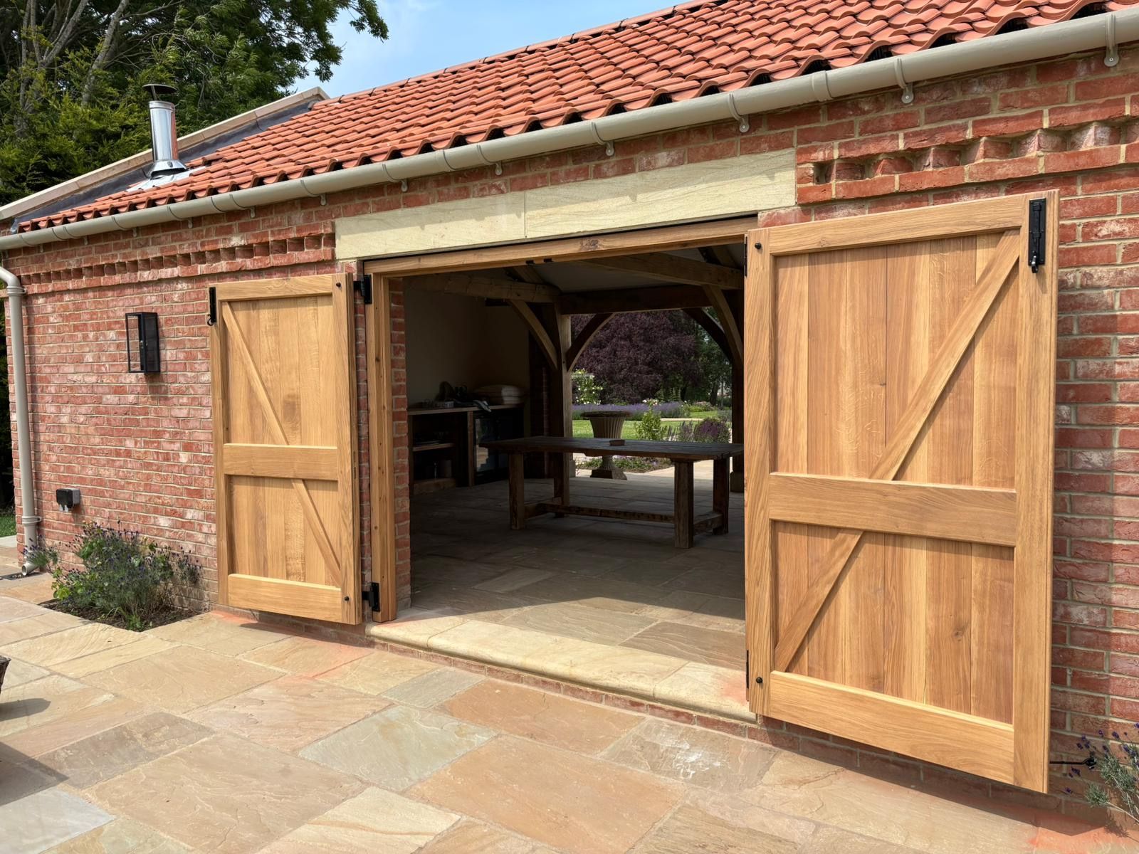 A brick building with wooden doors open to a patio.