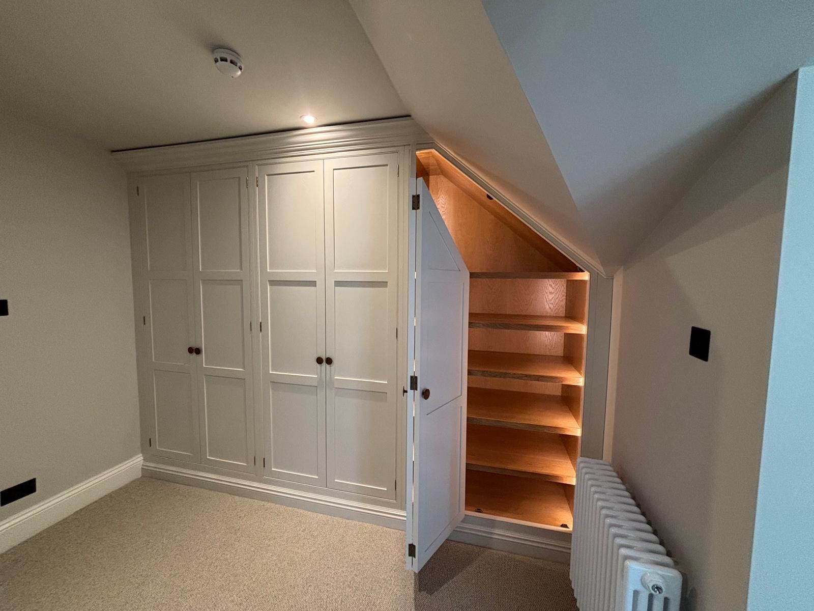A room with a staircase and a closet underneath it.