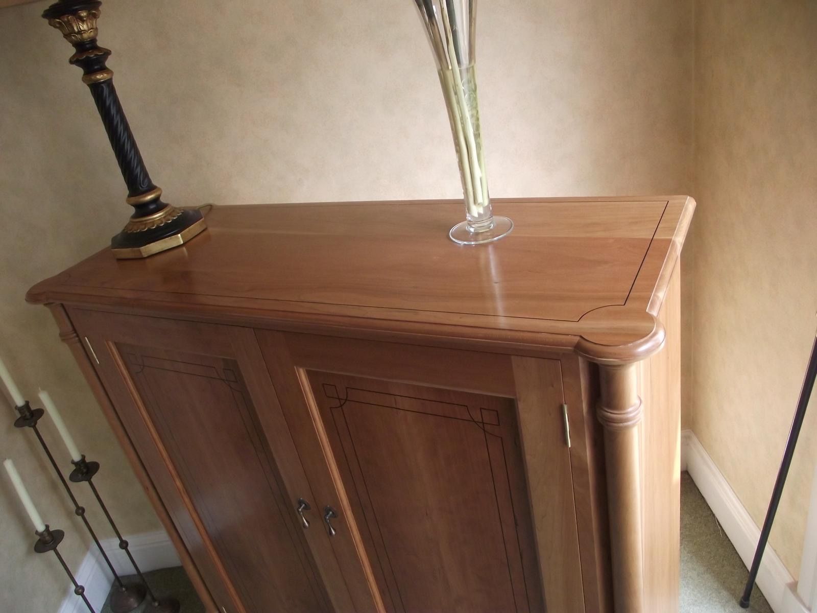 A wooden cabinet with a vase on top of it