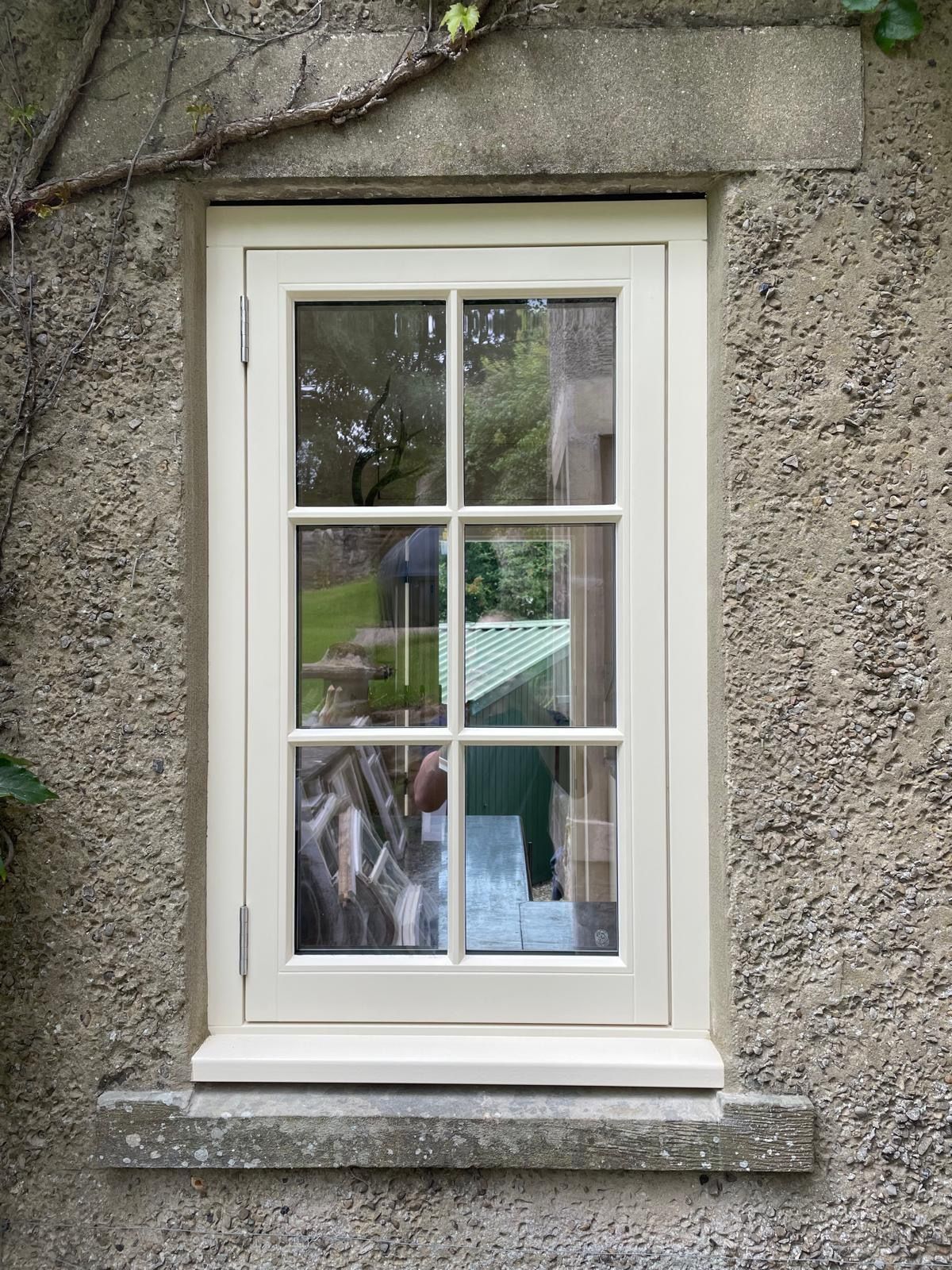 A white window is sitting on a concrete wall.