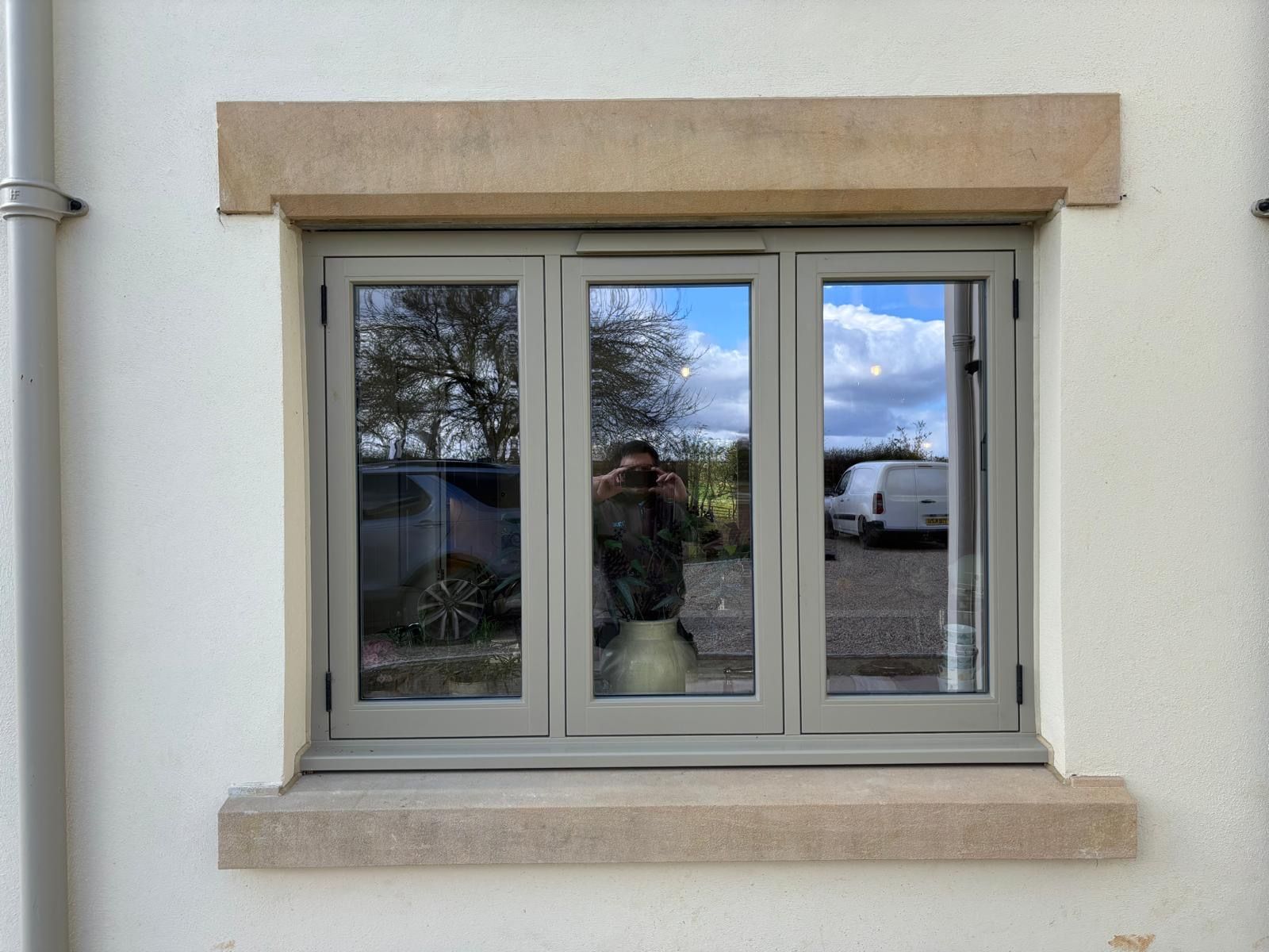 A window on the side of a building with a reflection of a car in the window.