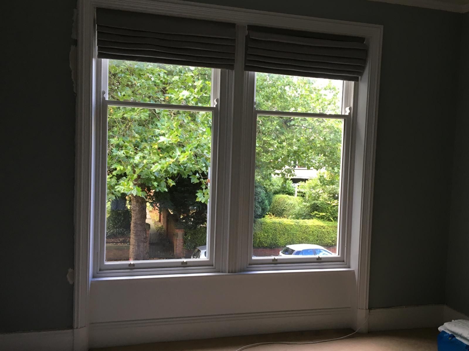 A room with two windows and a view of trees.