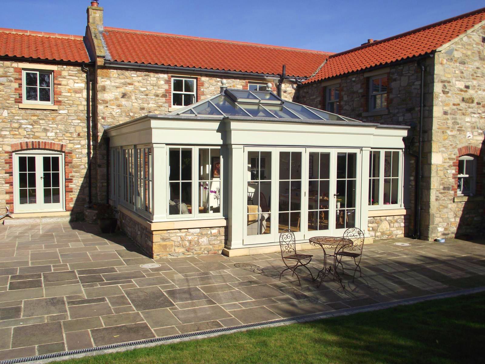 A large stone house with a large conservatory in front of it