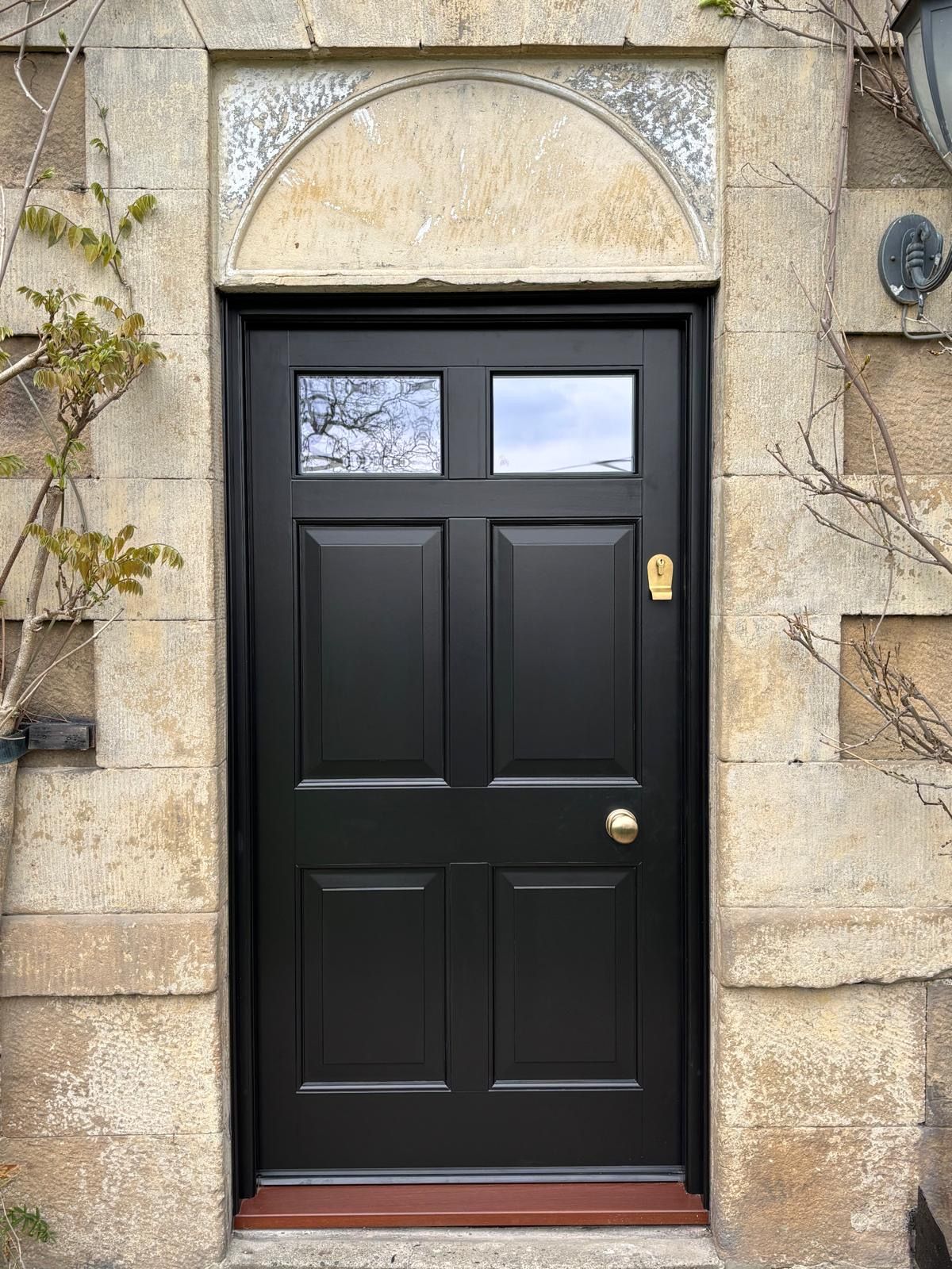 A black door is sitting on top of a stone wall.