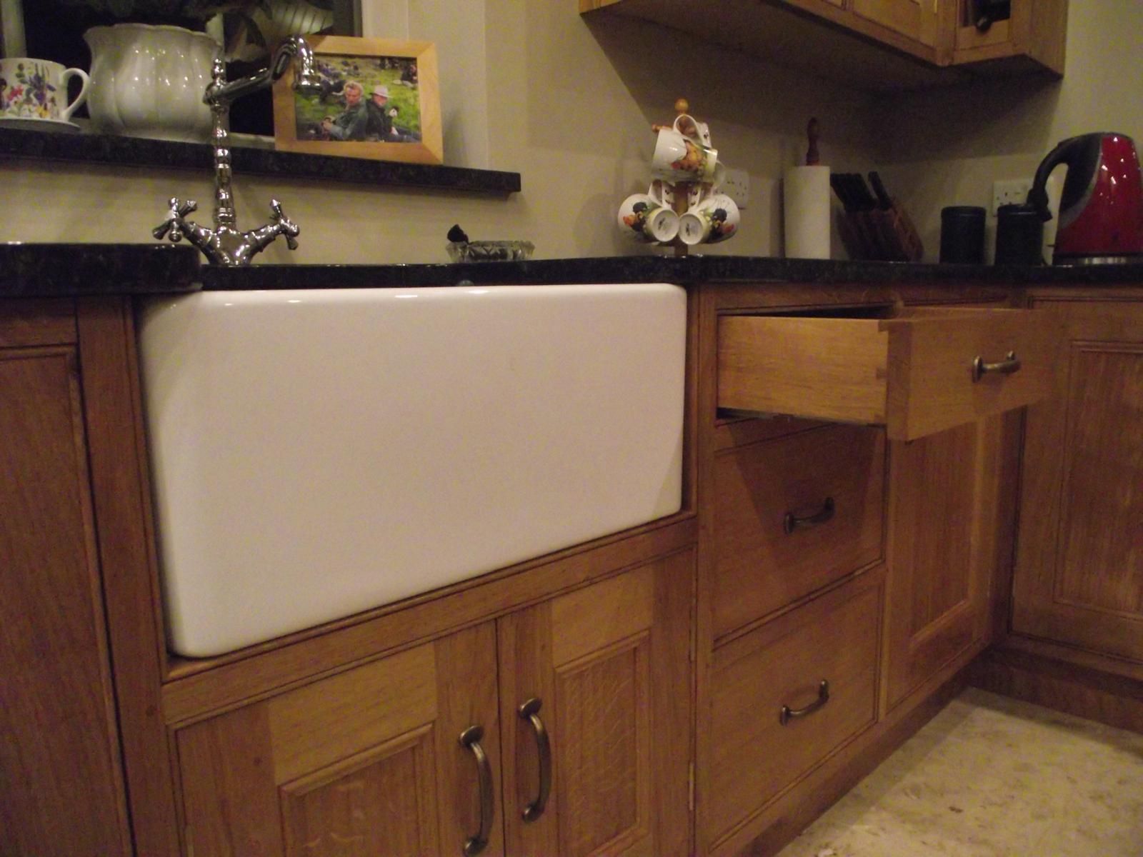 A kitchen with a white sink and wooden cabinets