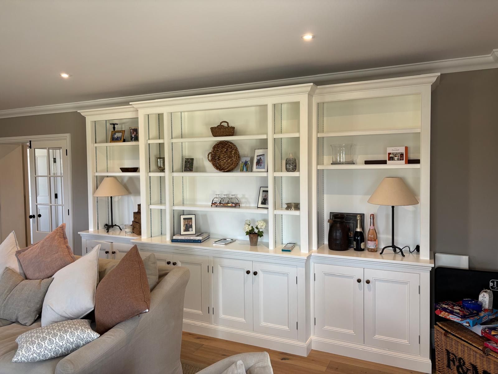 A living room with a couch , chairs , shelves and lamps.
