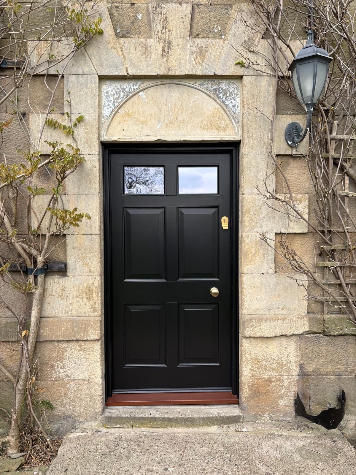 A black door is on the side of a stone building.
