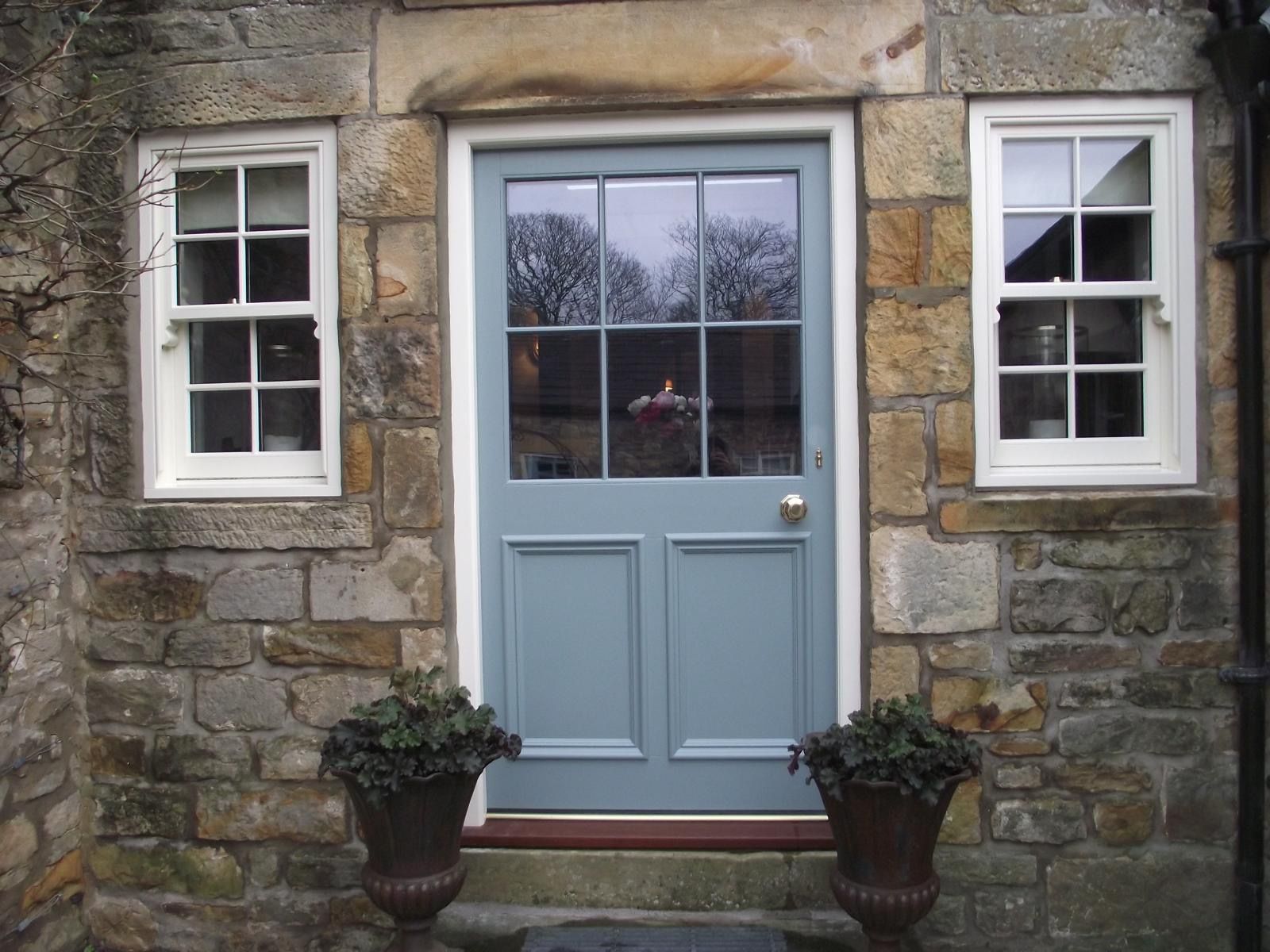 A stone building with a blue door and two windows