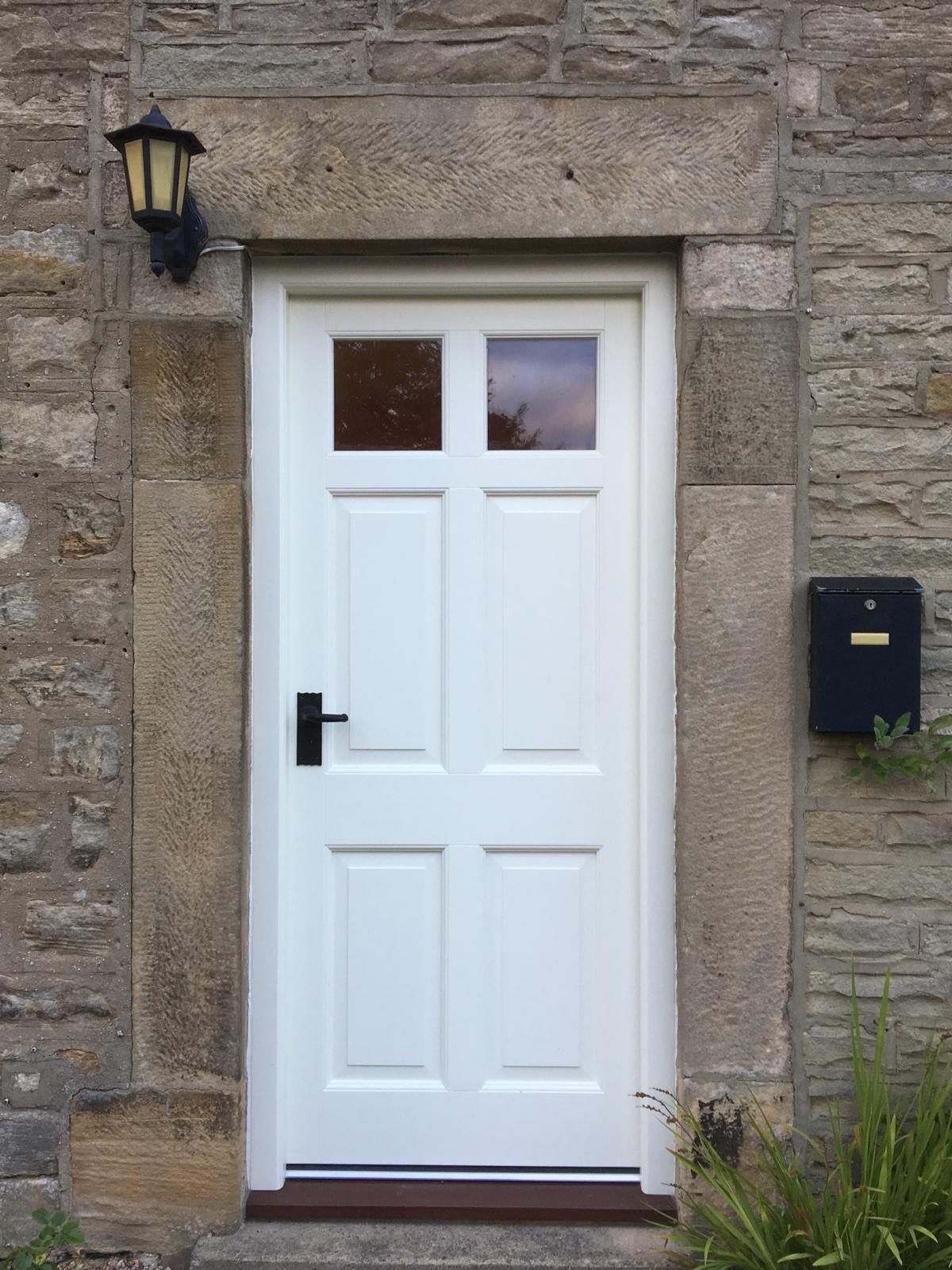 A white door is sitting in front of a stone wall.