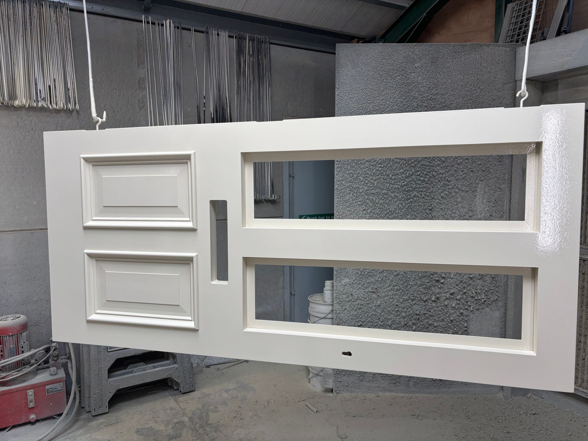 A white door is hanging from the ceiling in a room.