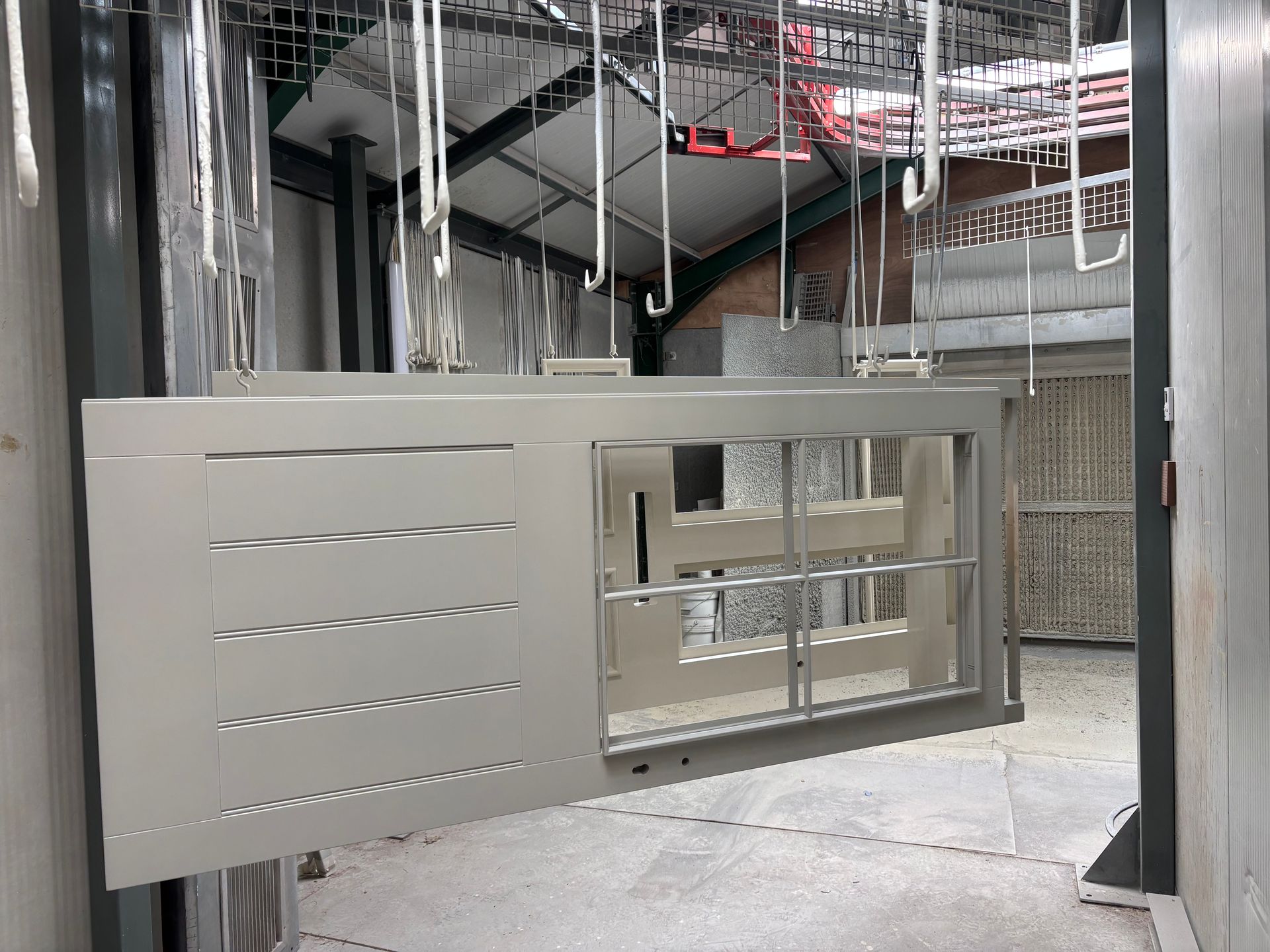 A stainless steel door is being painted in a factory.