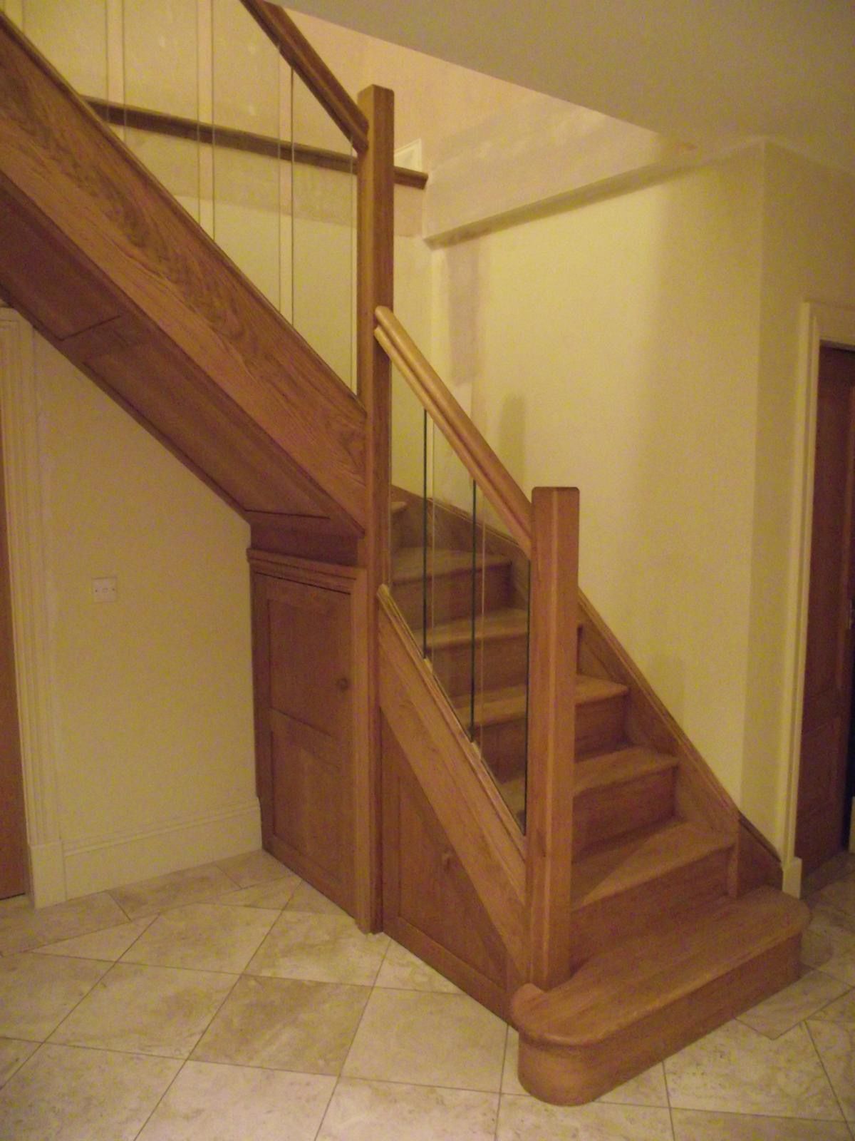 A wooden staircase with a glass railing in a room.
