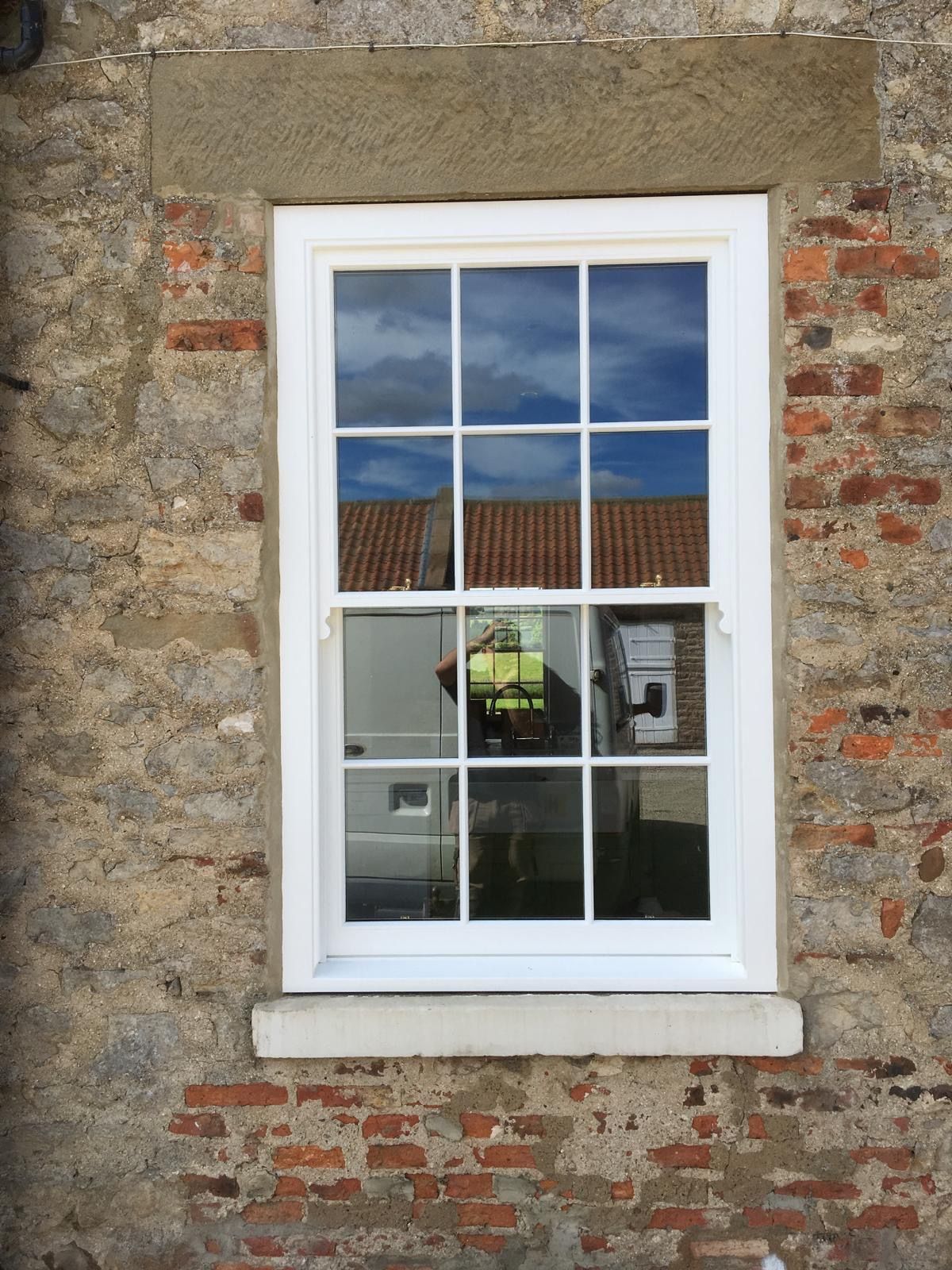 A white window is on the side of a brick building.
