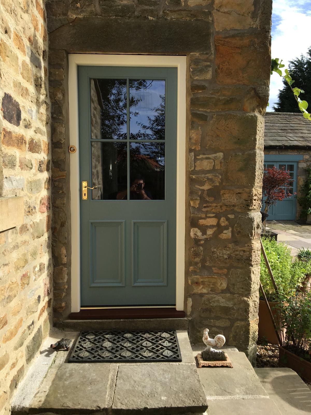 A blue door is on a stone wall next to a chicken statue.