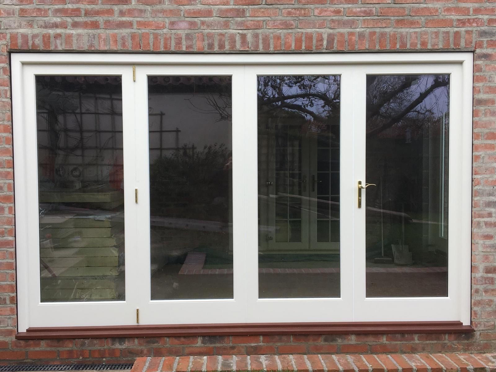 A white sliding glass door is on a brick wall.