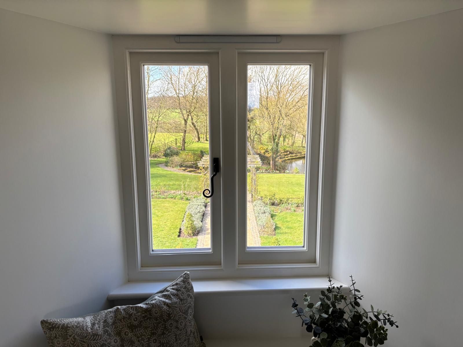 There is a window in the corner of the room with a view of the garden.