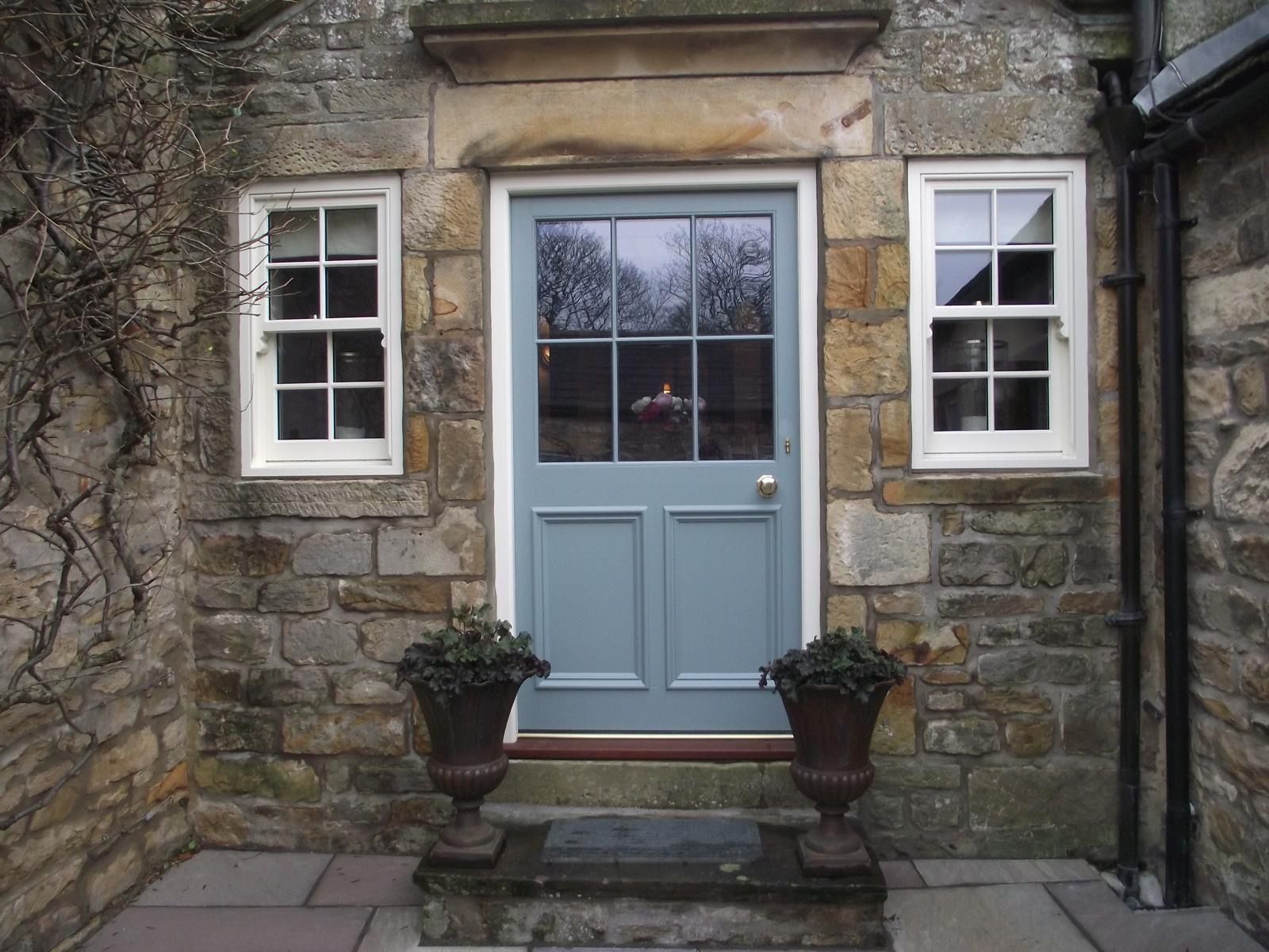 A stone building with a blue door and two windows