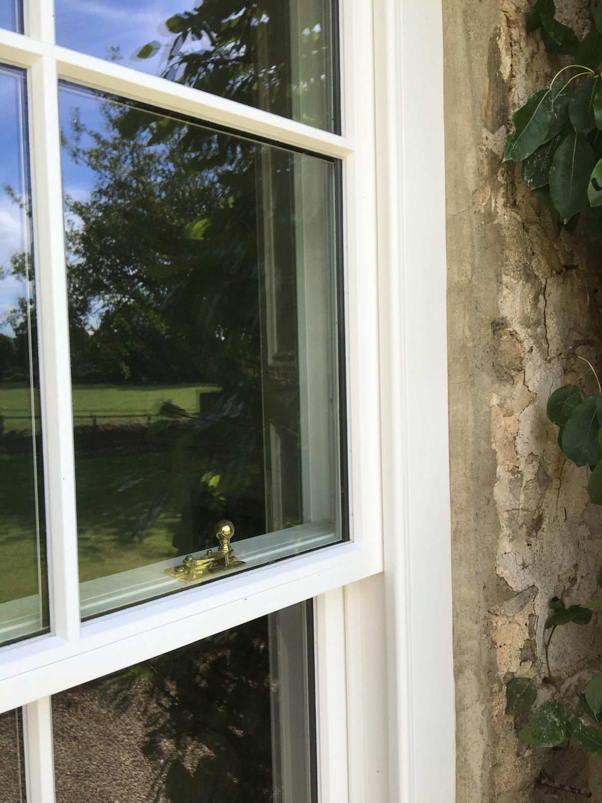 A close up of a white window on a stone wall.