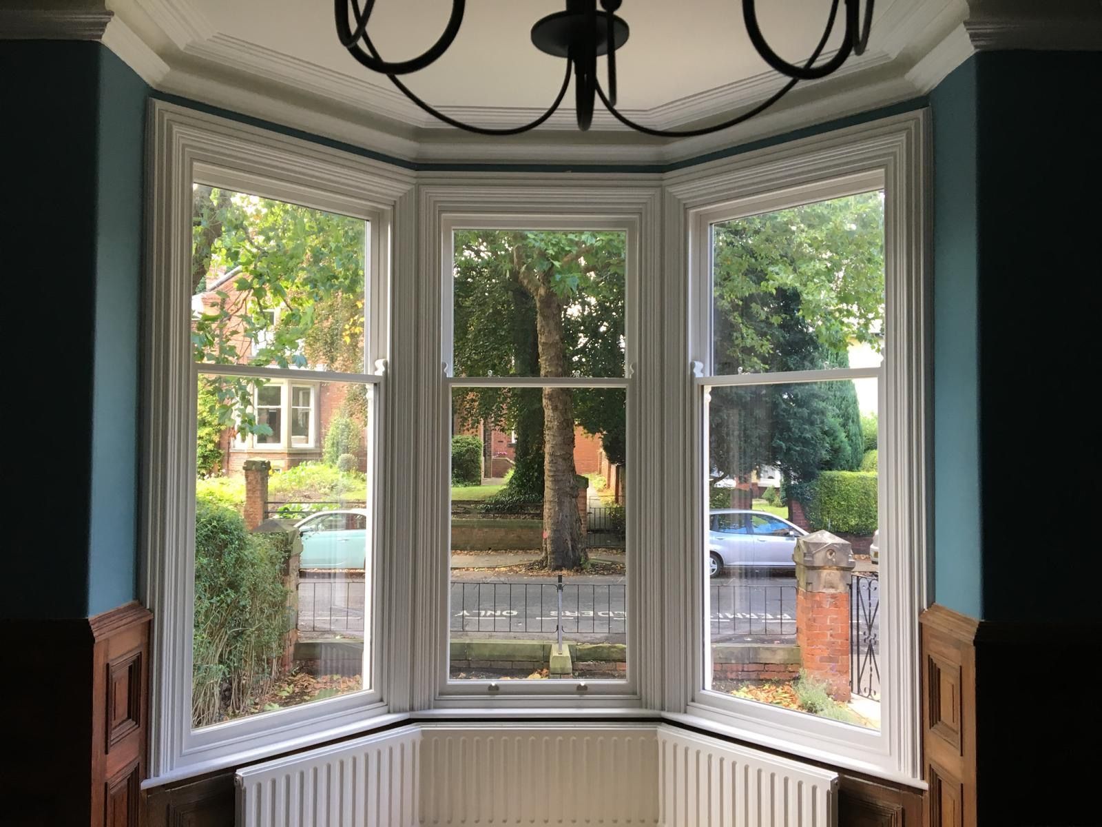 A room with a bay window and a chandelier.