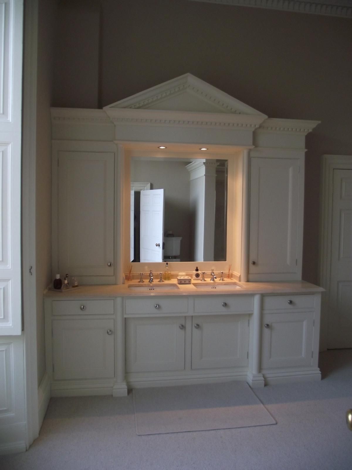 A bathroom with white cabinets and a large mirror