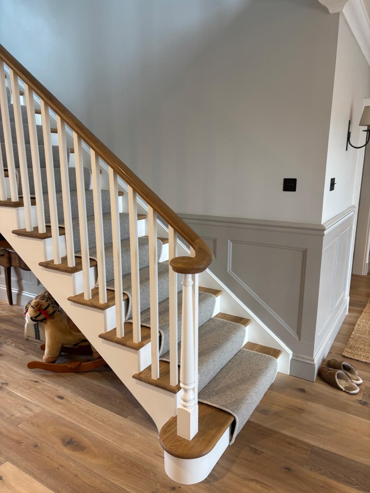 A white staircase with a wooden railing in a living room.