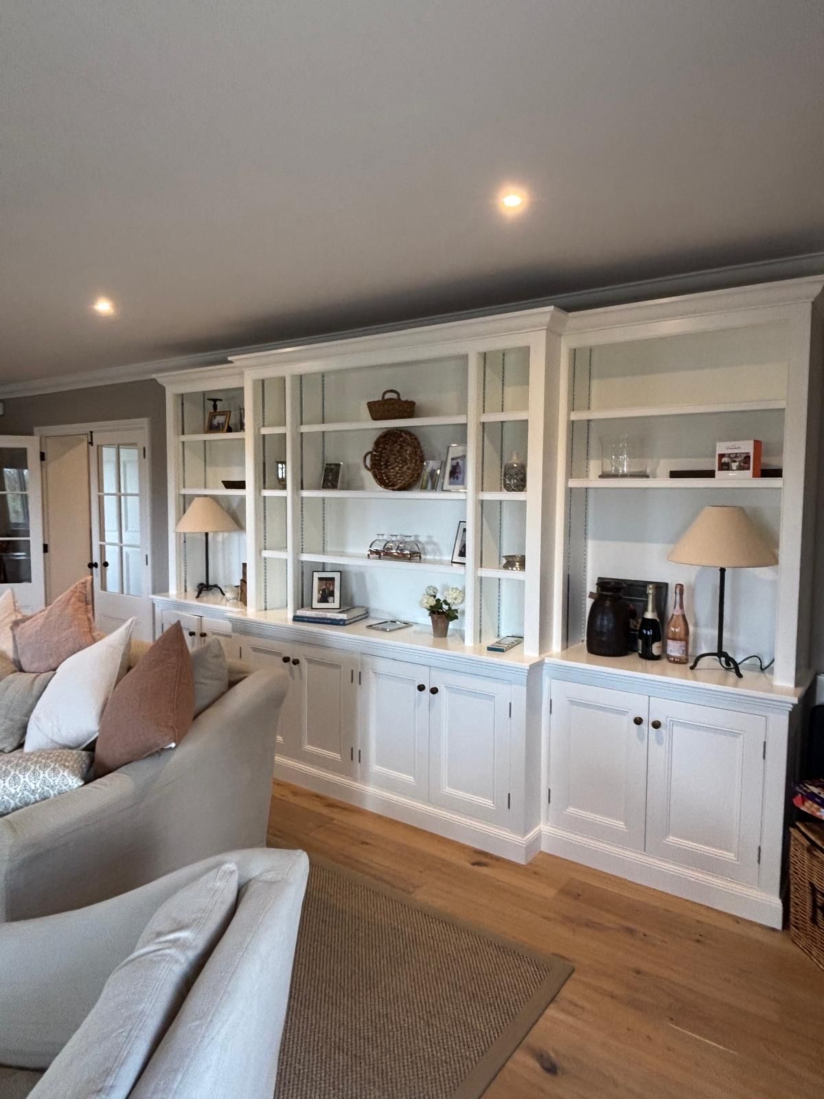 A living room with a couch , chair , lamps and shelves.