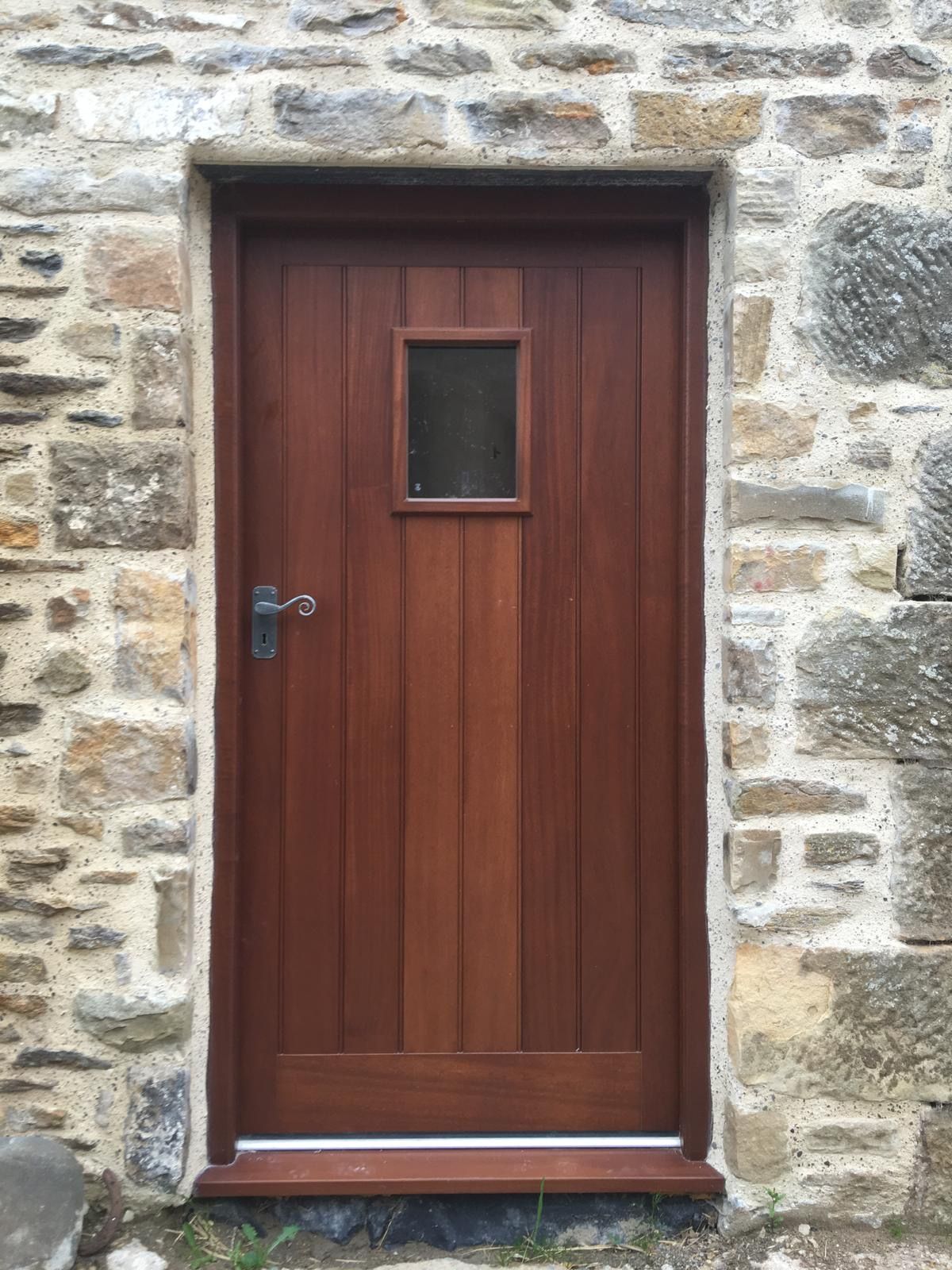 A wooden door is sitting in front of a stone wall.
