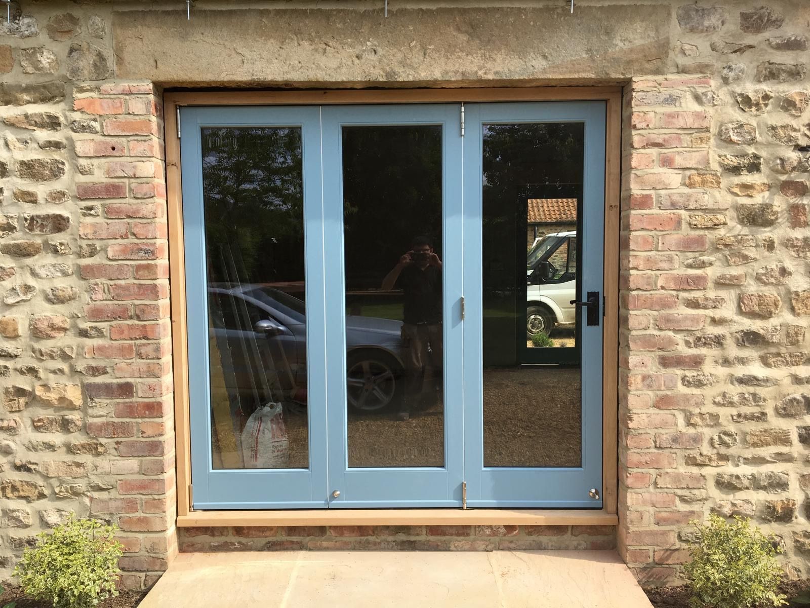 A brick building with a blue door and a car parked in front of it.