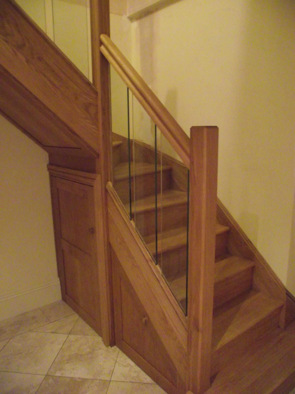 A wooden staircase with a glass railing in a room.