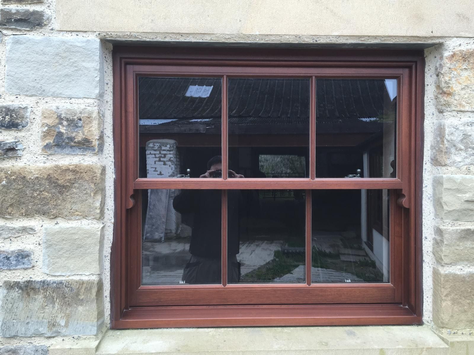 A wooden window is in a stone wall.