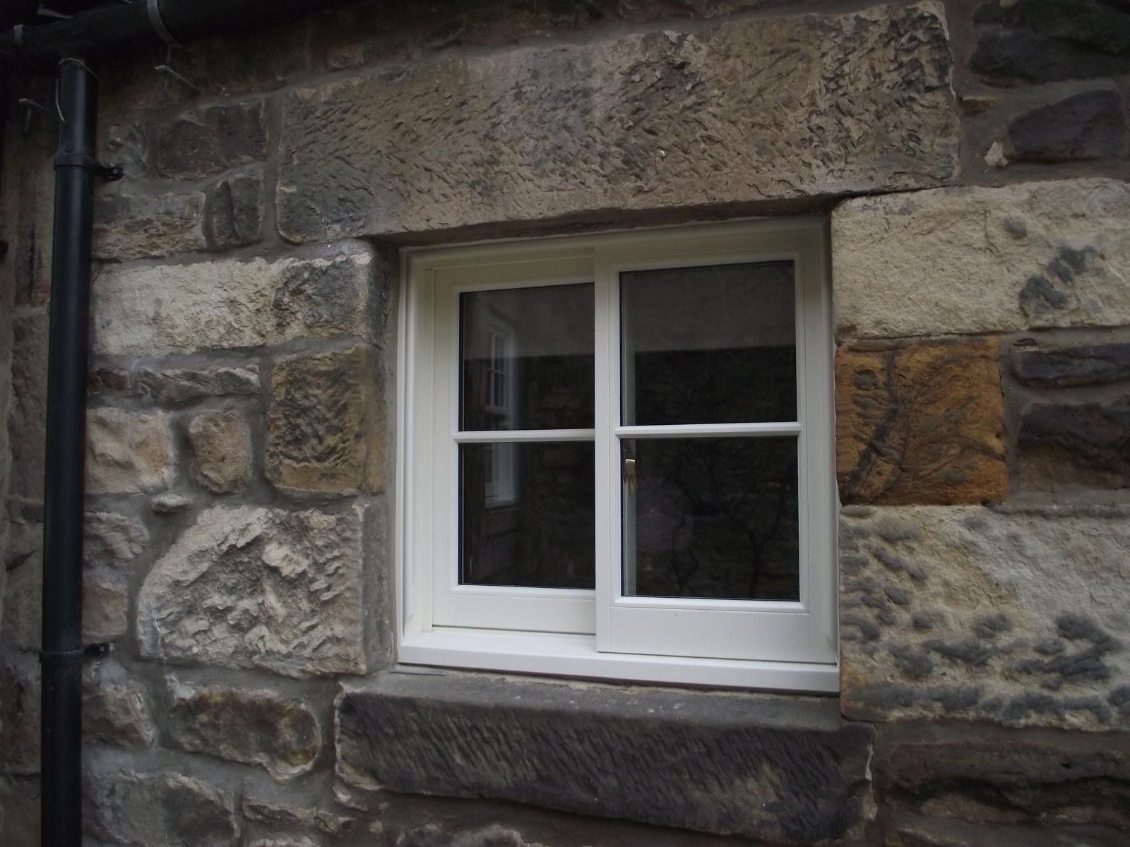 A window in a stone wall with a white frame