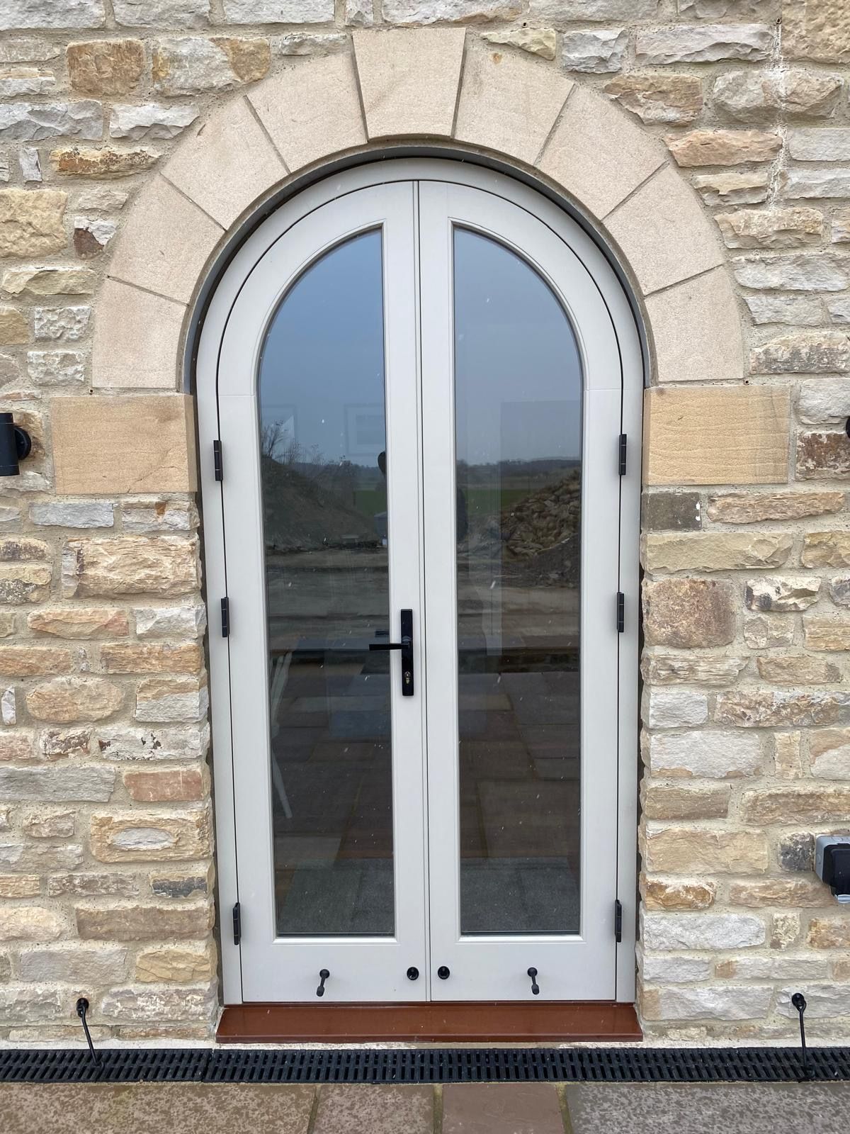 A stone building with a white door with arched glass