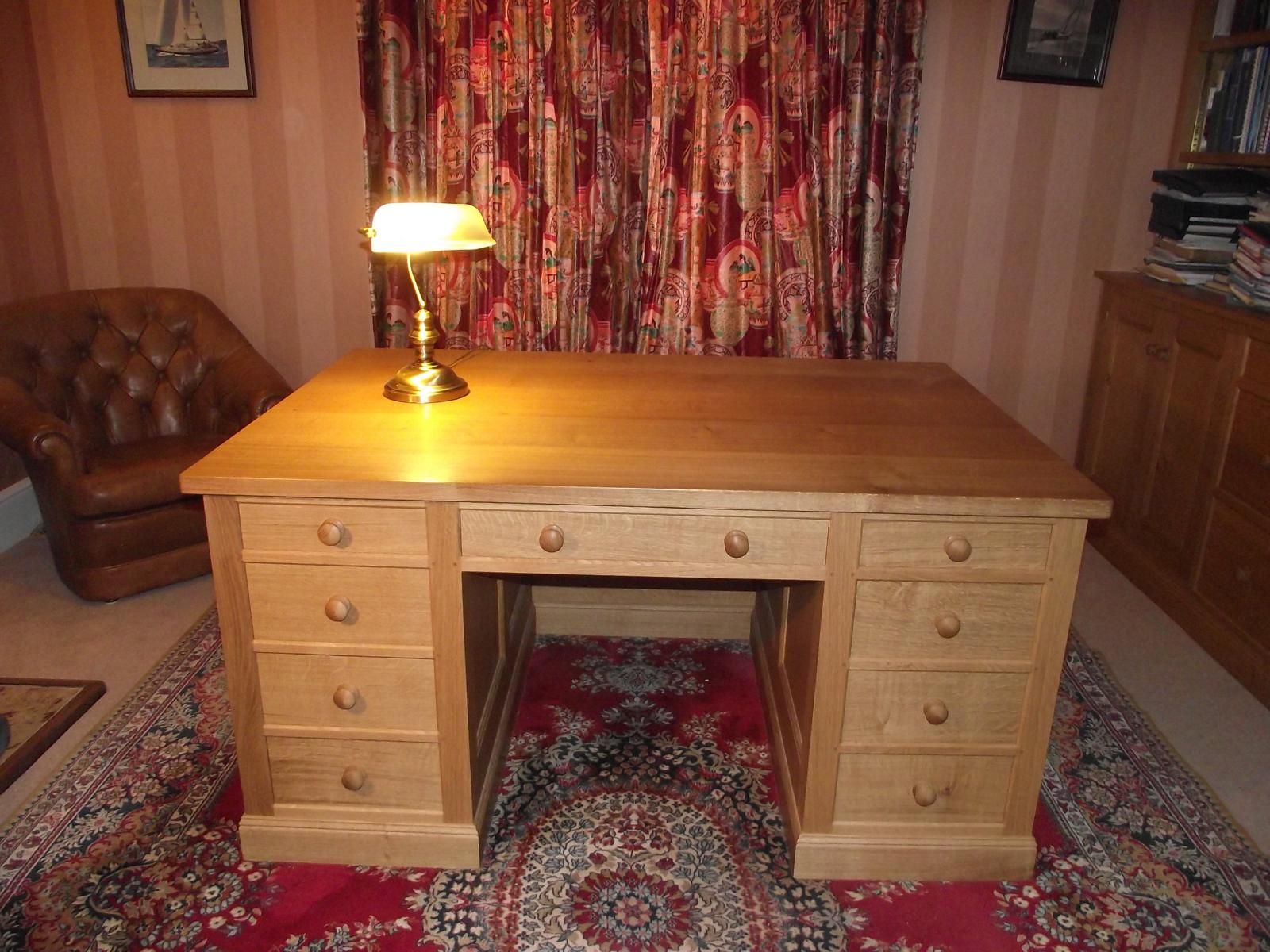 A wooden desk with a lamp on top of it