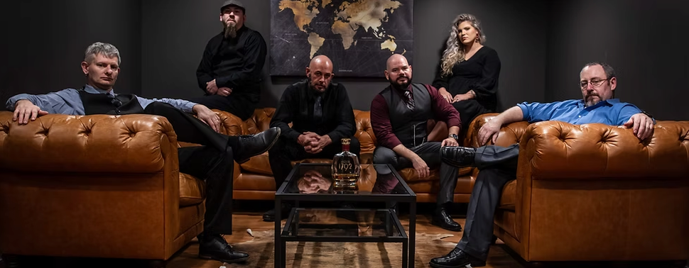 A group of men and women are standing next to each other in front of a wooden fence.