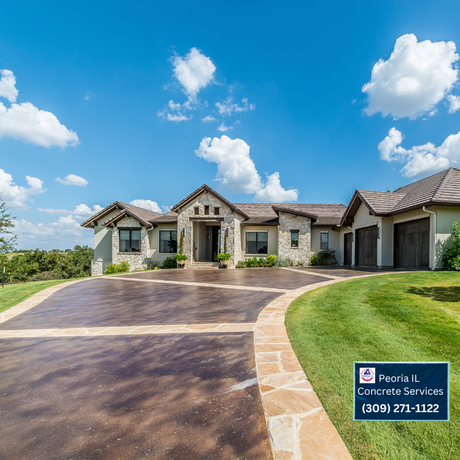 Exterior of a stone house with a brown concrete driveway, on a sunny day.